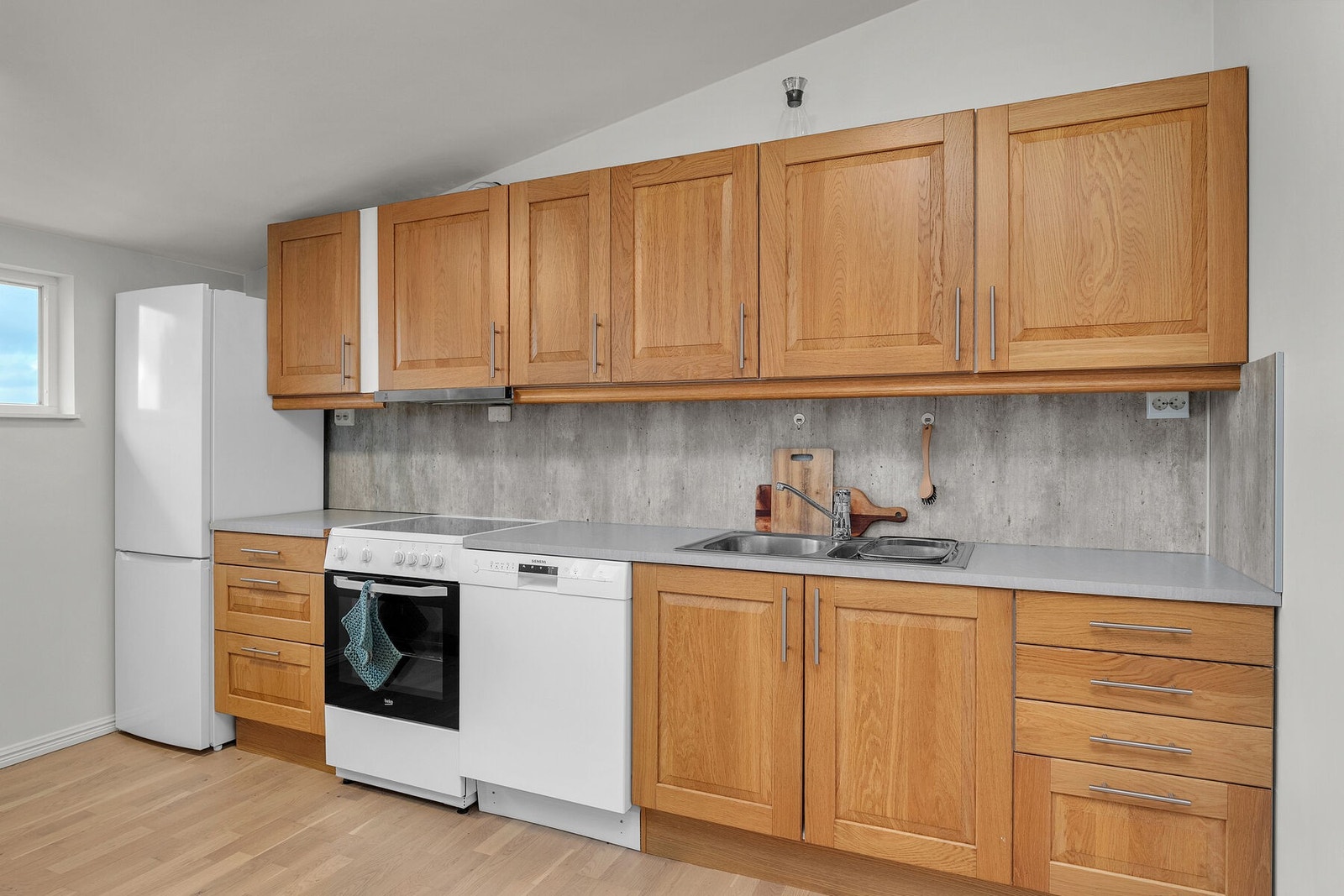 Kjøkken i leilighet 2 med profilerte fronter, laminert benkeplate med nedfelt vask og opplegg for frittstående hvitevarer. Galleribilde