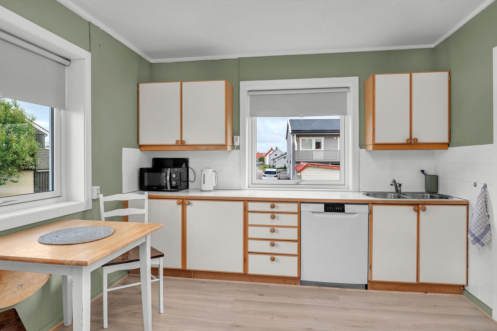 Kjøkkeninnredningen har lyse, slette fronter, laminert benkeplate med nedfelt vask og opplegg for frittstående hvitevarer. Galleribilde