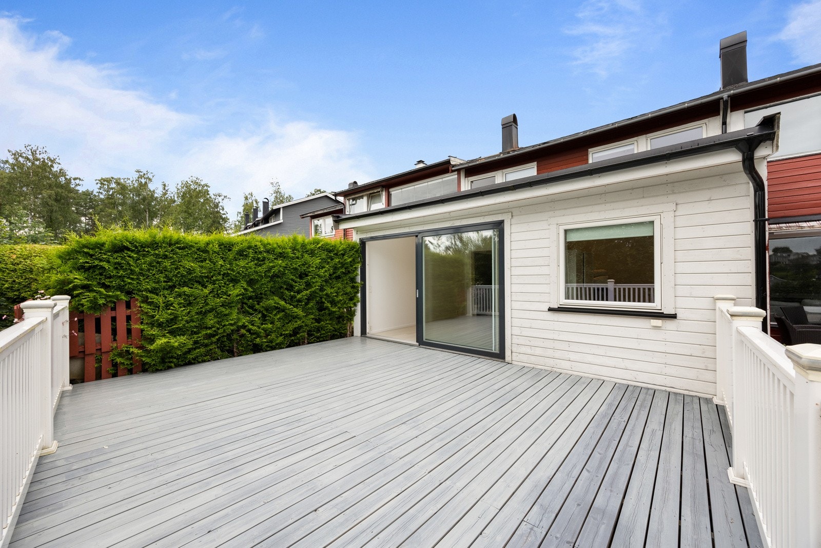 Terrassen har rekkverk langs to sider og en tett, skjermende hekk langs den siste siden. Galleribilde