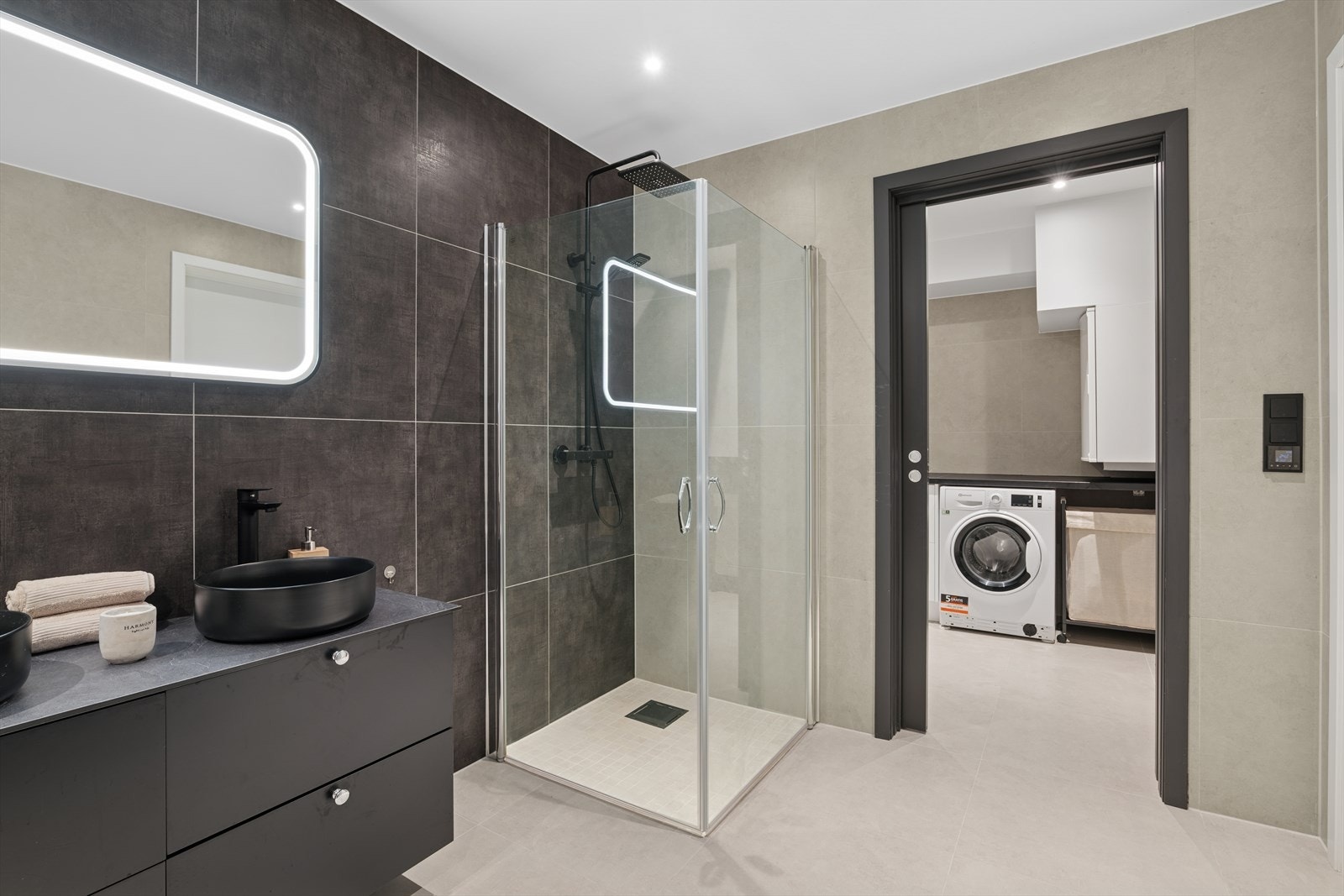 Rommet er innredet med en lekker baderomsinnredning med dobbel servant og skuffeseksjon, belyst speil, vegghengt toalett og dusjhjørne med innfellbare glassdører og regnfallsdusj. Badet har flotte detaljer, samt en helhetlig luksuriøs utførelse. Galleribilde