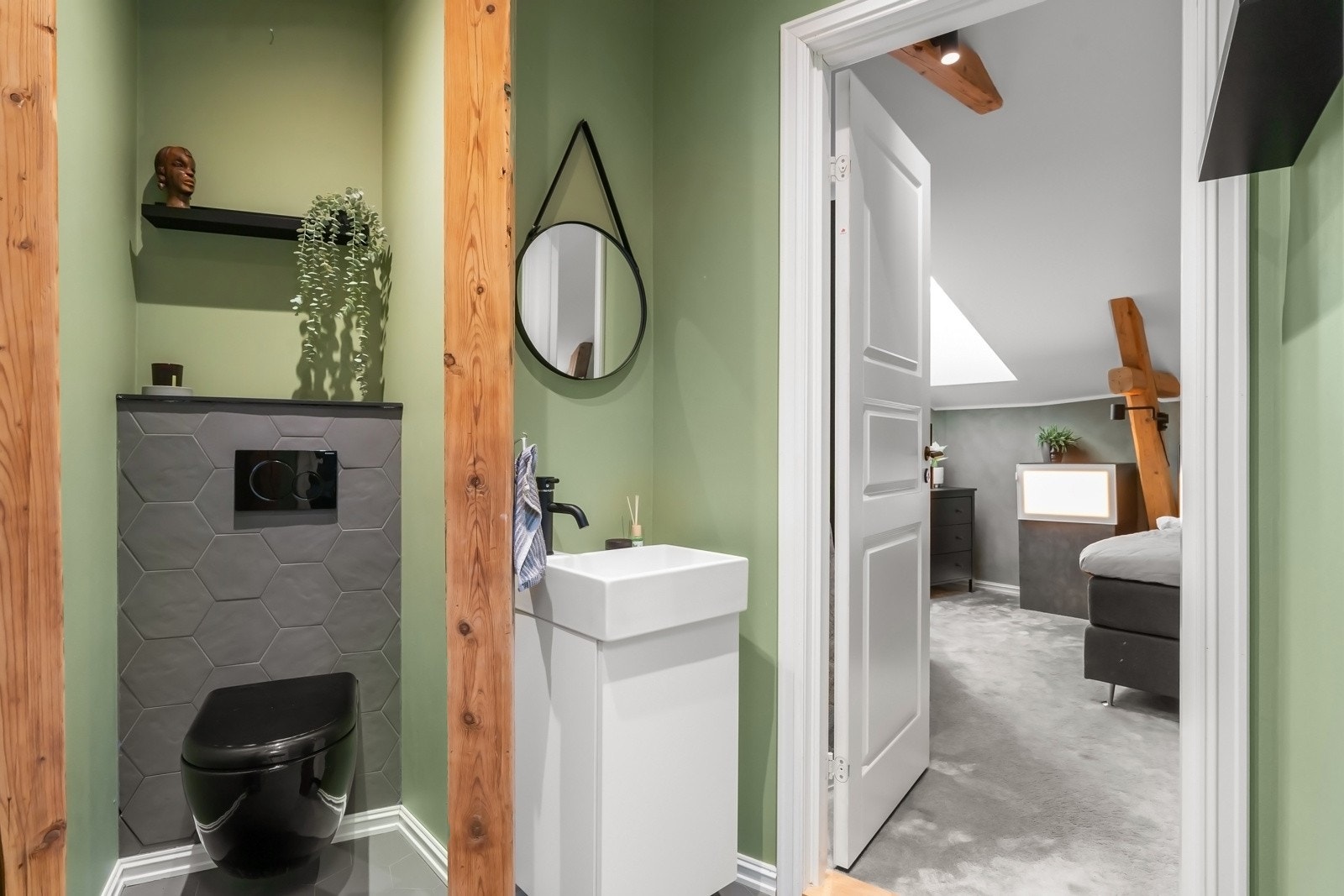 WC-rommet i loftsetasjen har slette vegger og mørkegrå fliser på gulvet. Rommet er utstyrt med et servantskap, vegghengt toalett og varmekabler i gulvet Galleribilde