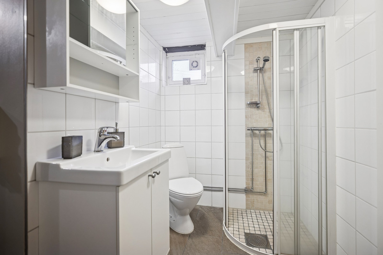 Flislagt bad i kjelleretasjen med servantinnredning, dusjhjørne og gulvstående toalett. Galleribilde
