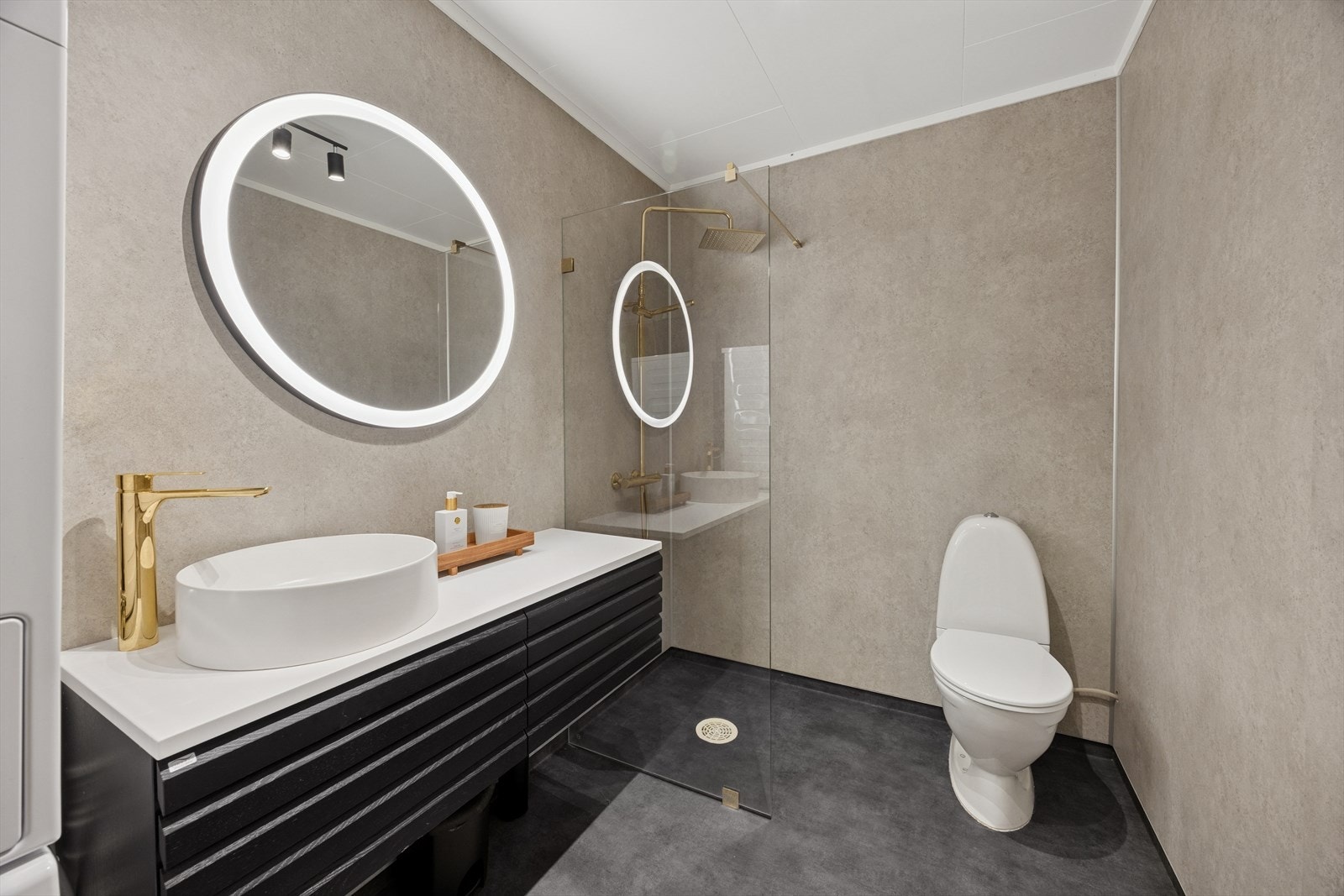 Rommet har innredning med sort fronter og bolle servant med gull ett greps blandebatteri, toalett (2000 opplyser eier), dusjvegger og opplegg for vaskemaskin. Galleribilde