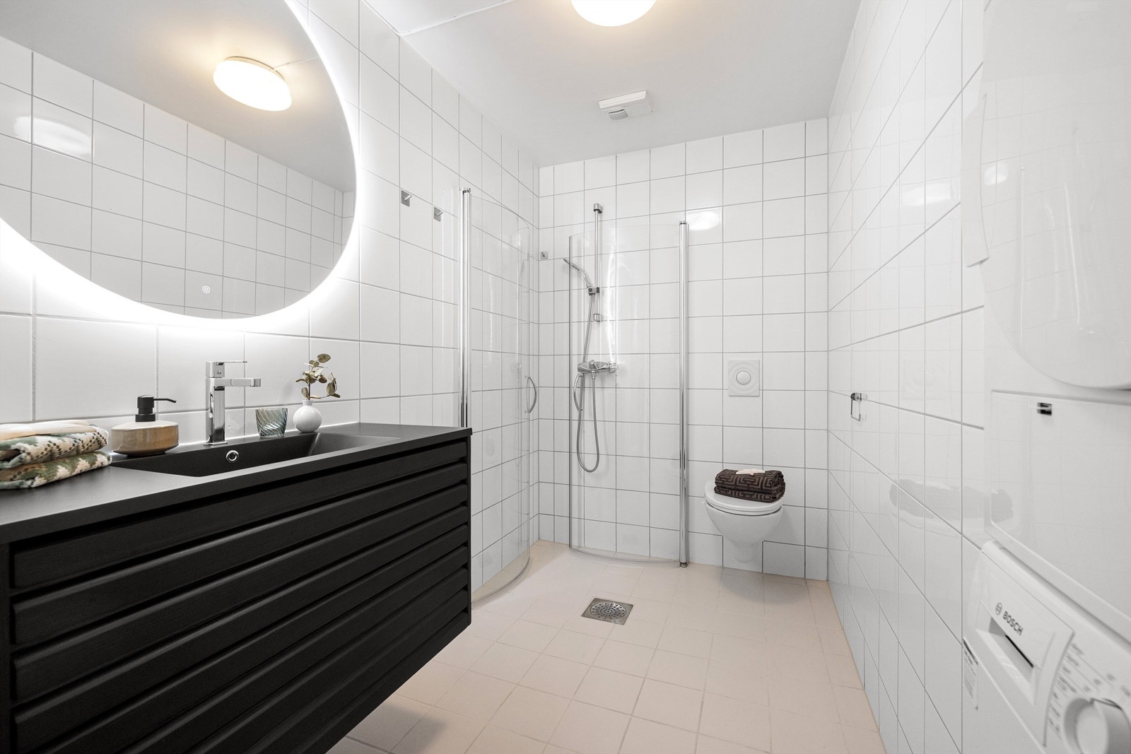 Lekkert og tidsriktig baderom med flislagte overflater, moderne innredning og opplegg for vaskemaskin. Varmtvann er inkl. i felleskostnader. Galleribilde