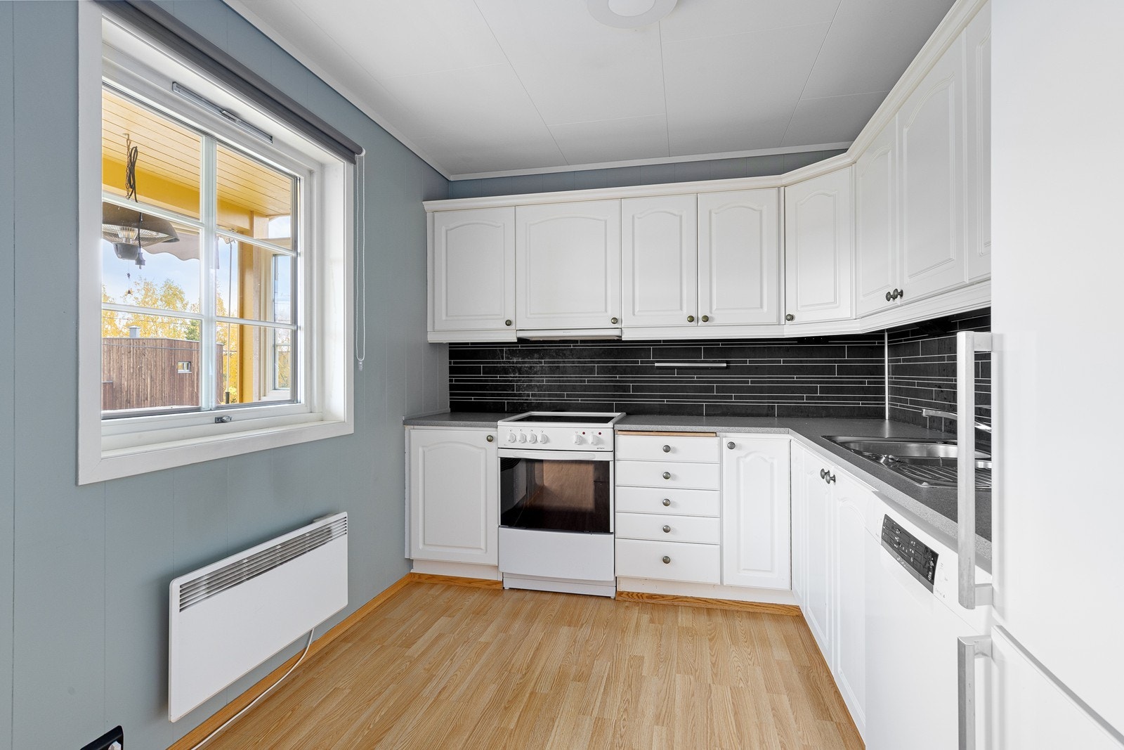 Lyst kjøkken med profilerte fronter og laminat benkeplate. Galleribilde