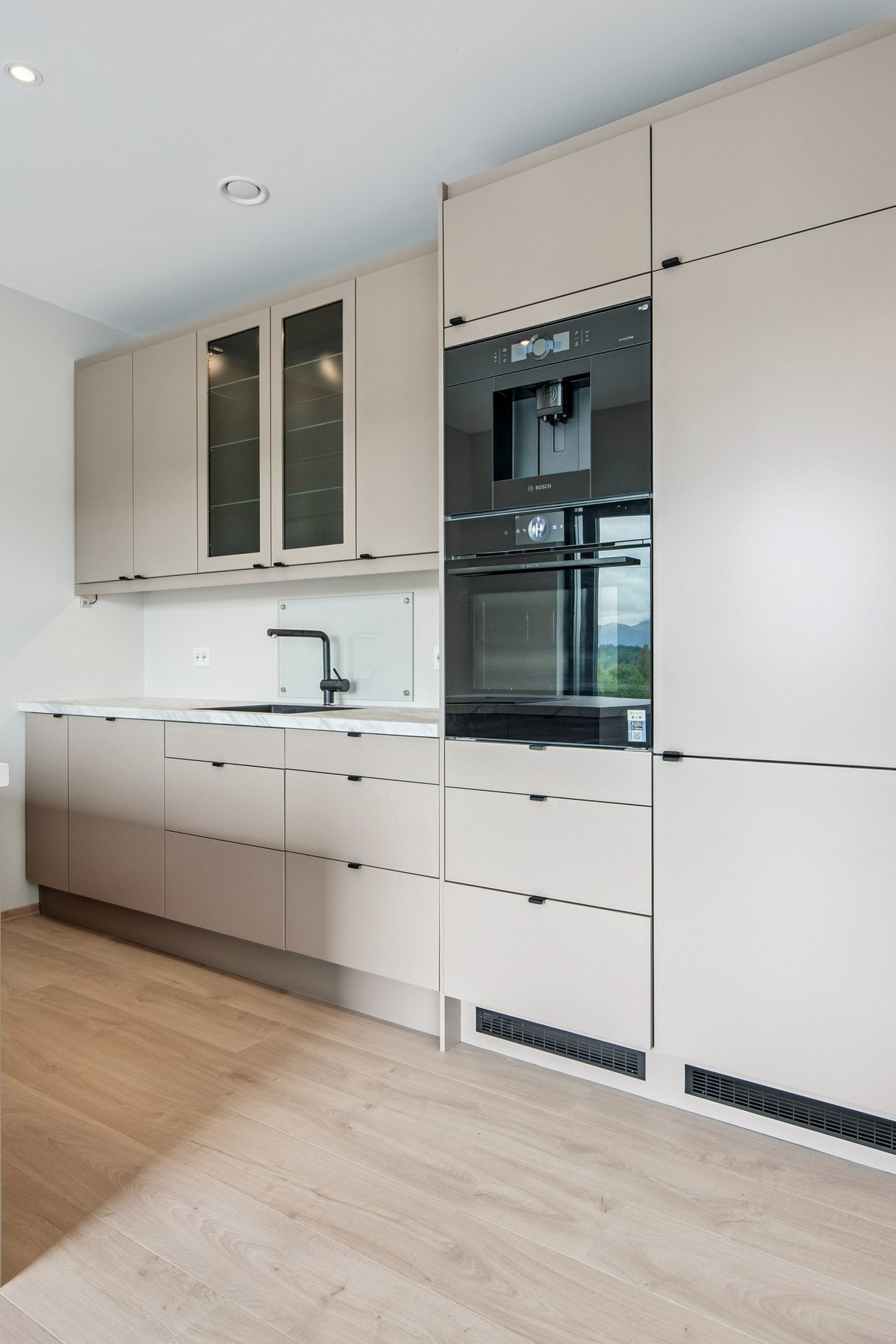 Kjøkken har integrert kaffemaskin, stekeovn, oppvaskmaskin, kjøle-/fryseskap og nedfelt induksjonstopp med innbygd ventilator Galleribilde