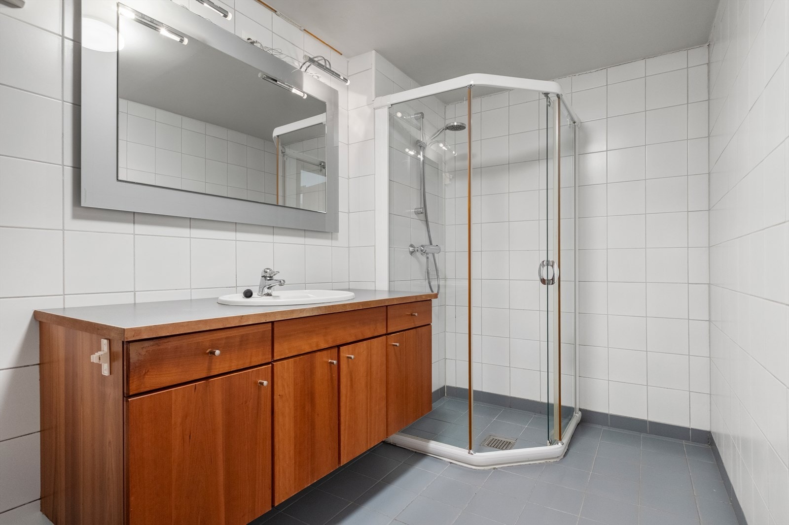 Bad. Veggene har fliser og taket er malt. På gulv er det fliser og det er vannbåren varme i gulvet. Rommet har innredning med nedfelt servant, toalett, dusjvegger/ hjørne og opplegg for vaskemaskin. Galleribilde