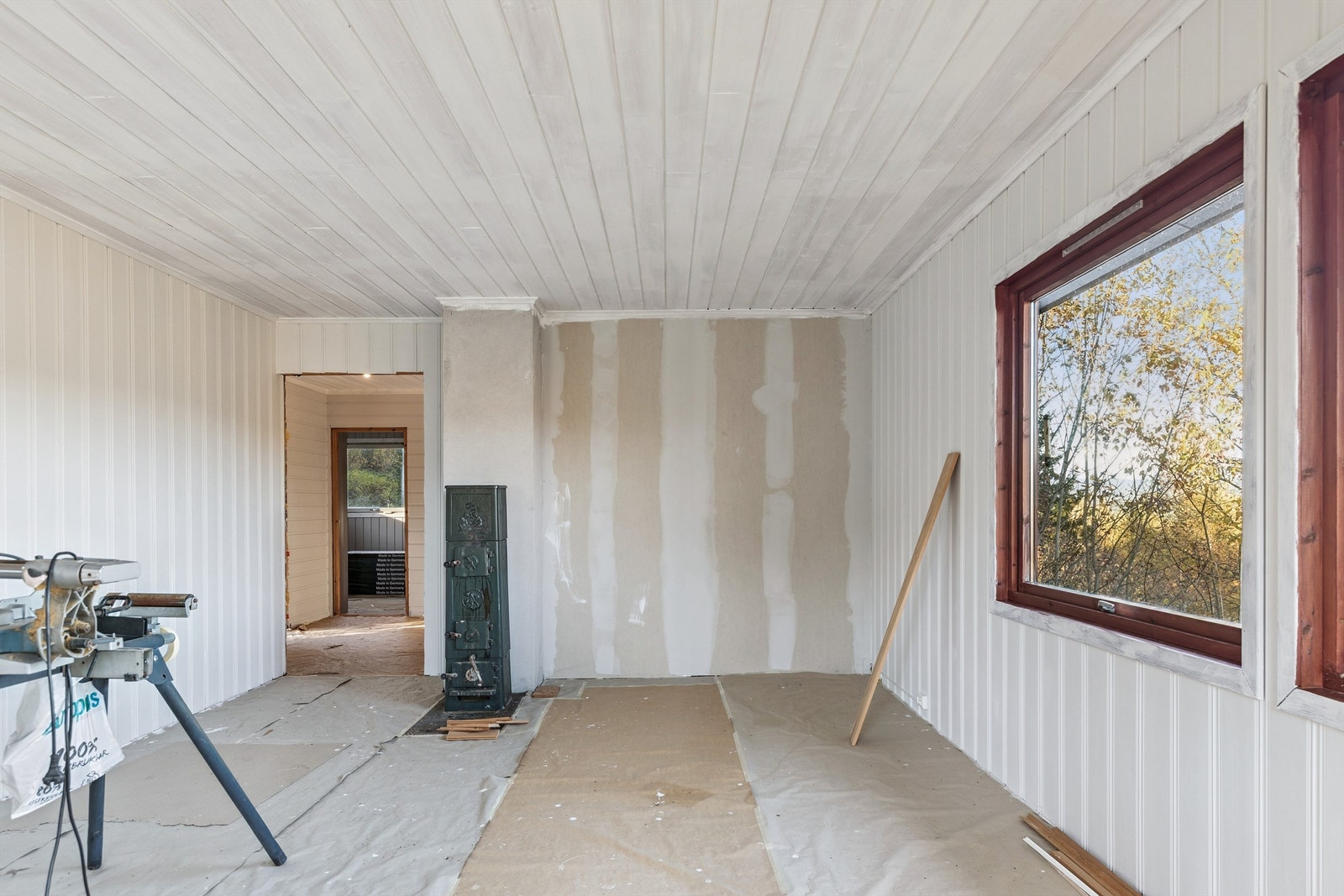 En eldre vedovn er plassert i stuen. Pipeløpet er utført i elementer med sotluke i kjeller. Galleribilde