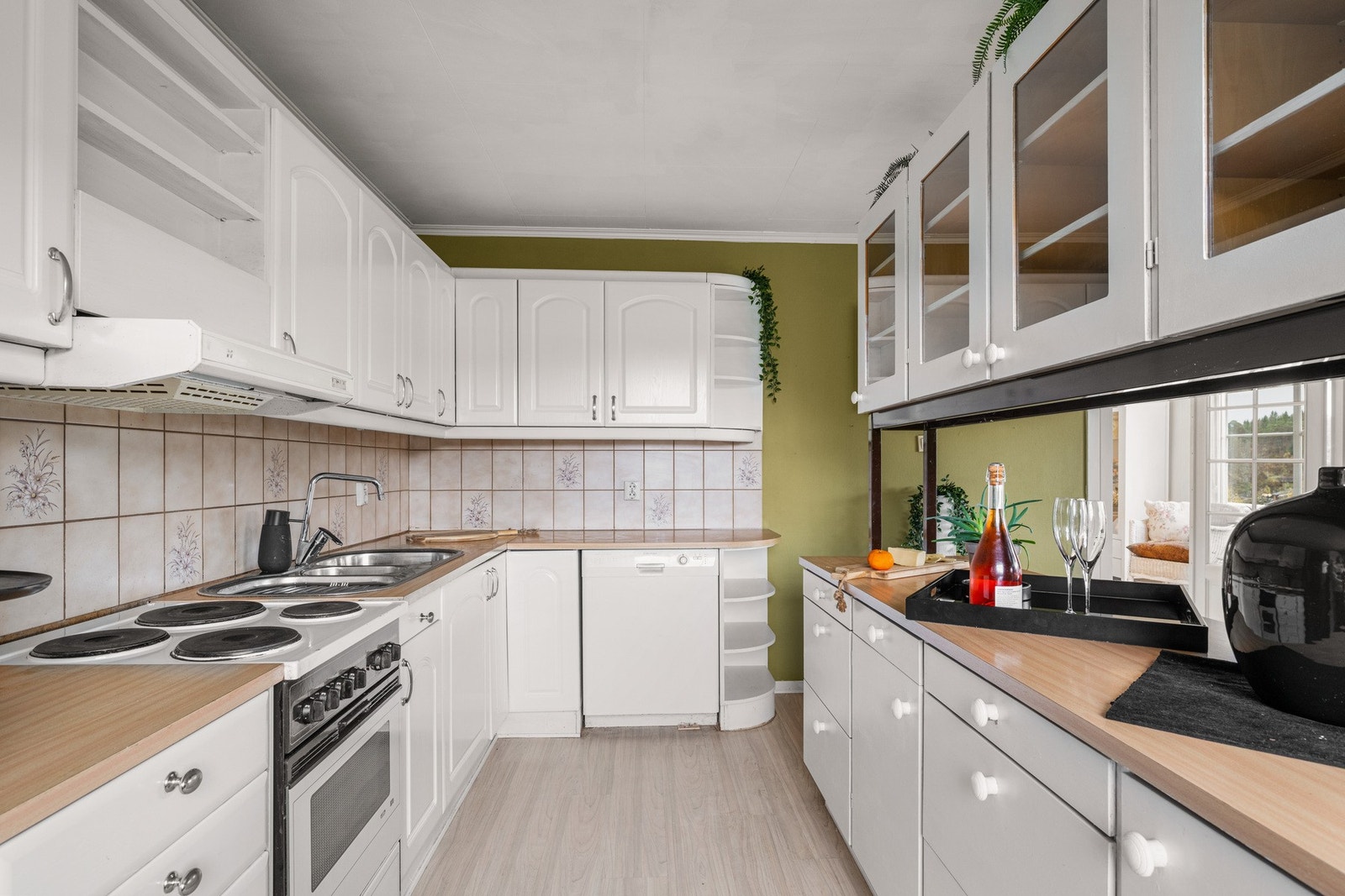 Kjøkkenet har profilerte fronter, enkelte overskap med glassfronter, laminat benkeplate og fliser over benk. Galleribilde