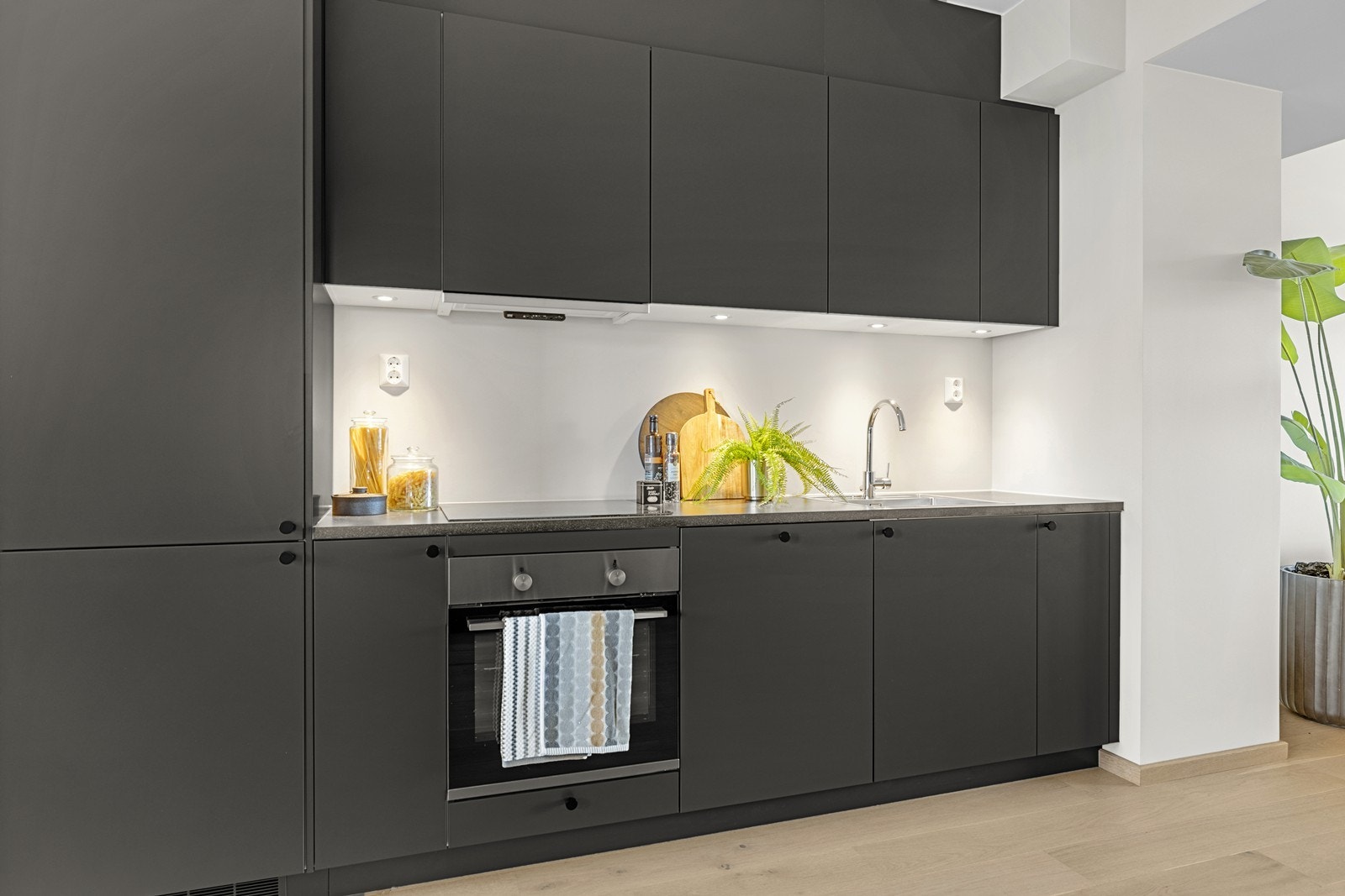 Kjøkkenet har mørk farge på skap ( peppergrå ) og benkeplate med grå/sort overflate. Knotter i sort og touchbeslag (push) på overskap. Galleribilde