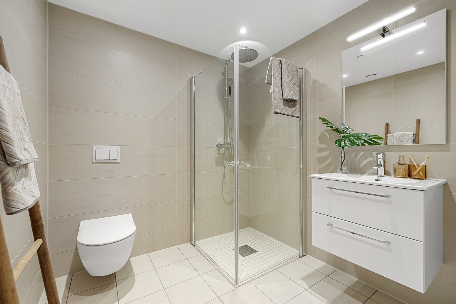 Baderom v/entré - flislagt bad med nedfelt servant, veggmontert toalett og dusjvegger/hjørne. Galleribilde