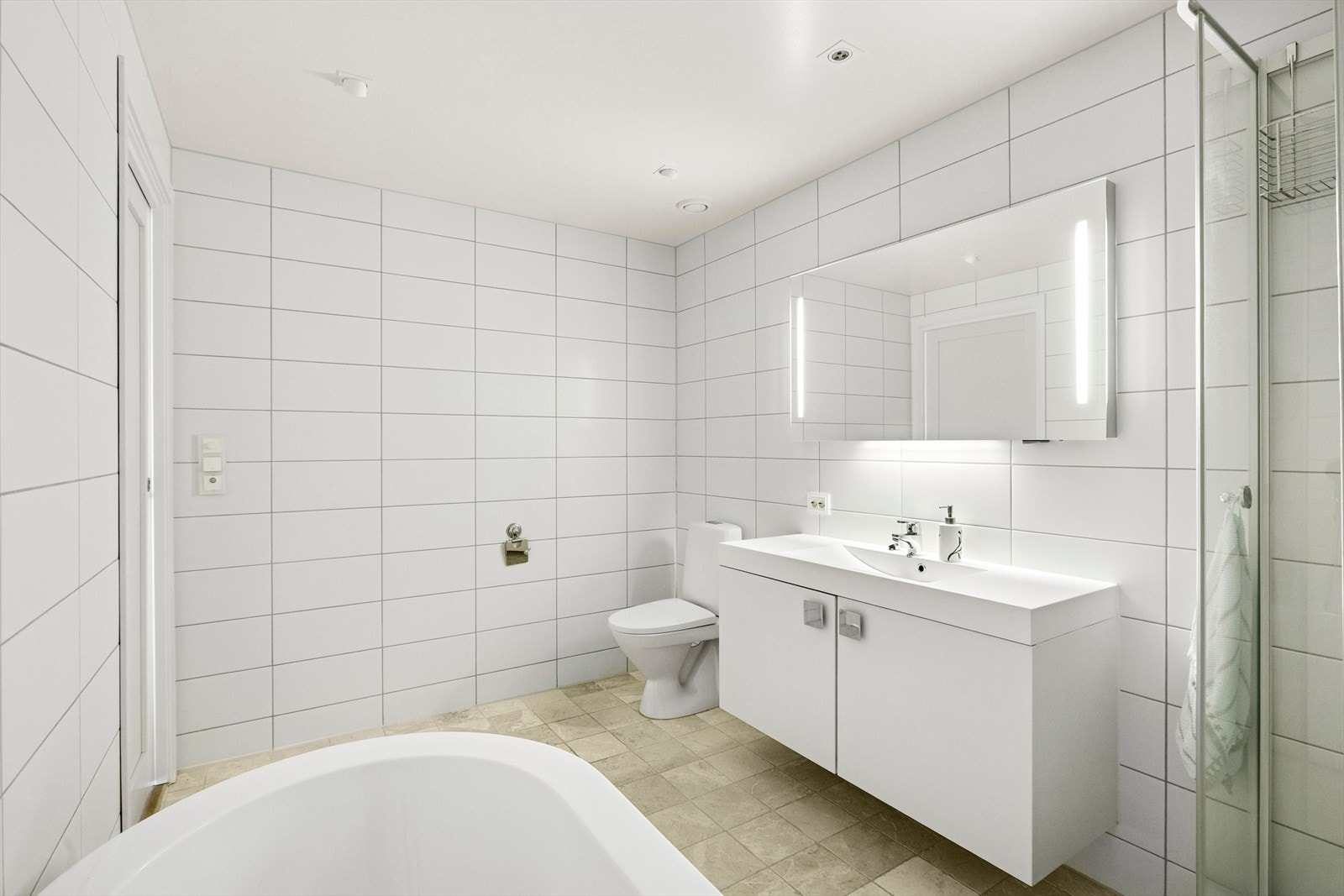 Badet som er tilknyttet hovedsoverommet har flislagte overflater i lyse tidløse farger. Galleribilde