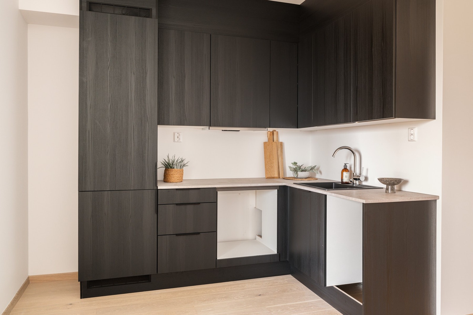 Stilren kjøkkeninnredning med mørke finerte fronter og laminert benkeplate. Galleribilde