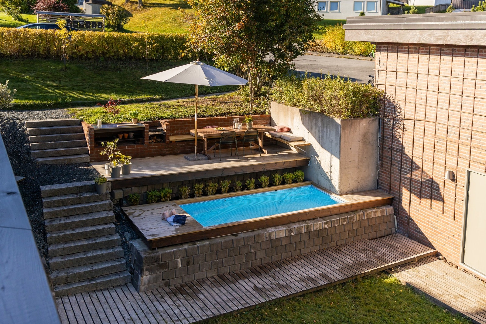 Nydelig plenareal på ei frodig endetomt som utgjør ca. 826 kvm. Her er det funksjonelle uteplasser med terrasser på ulike nivå med både basseng, grillplass og utepeis. Galleribilde