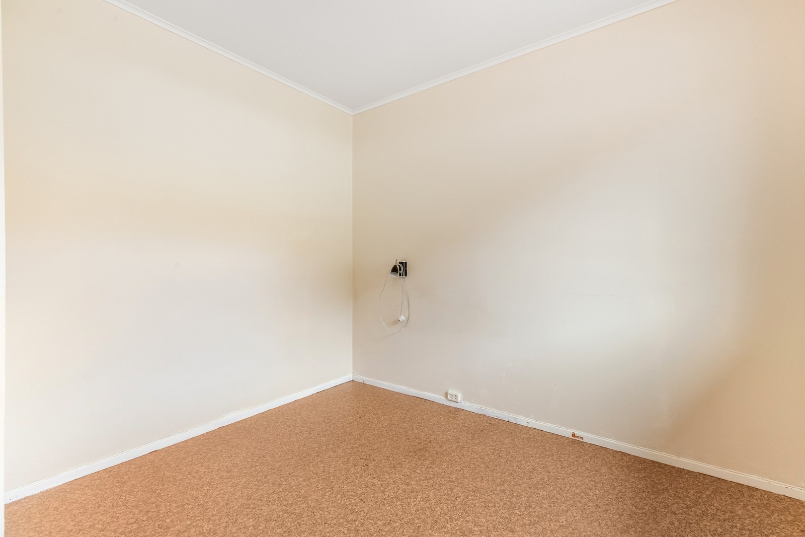 Soverom to har noe eldre gulv i belegg og lys tapet Galleribilde