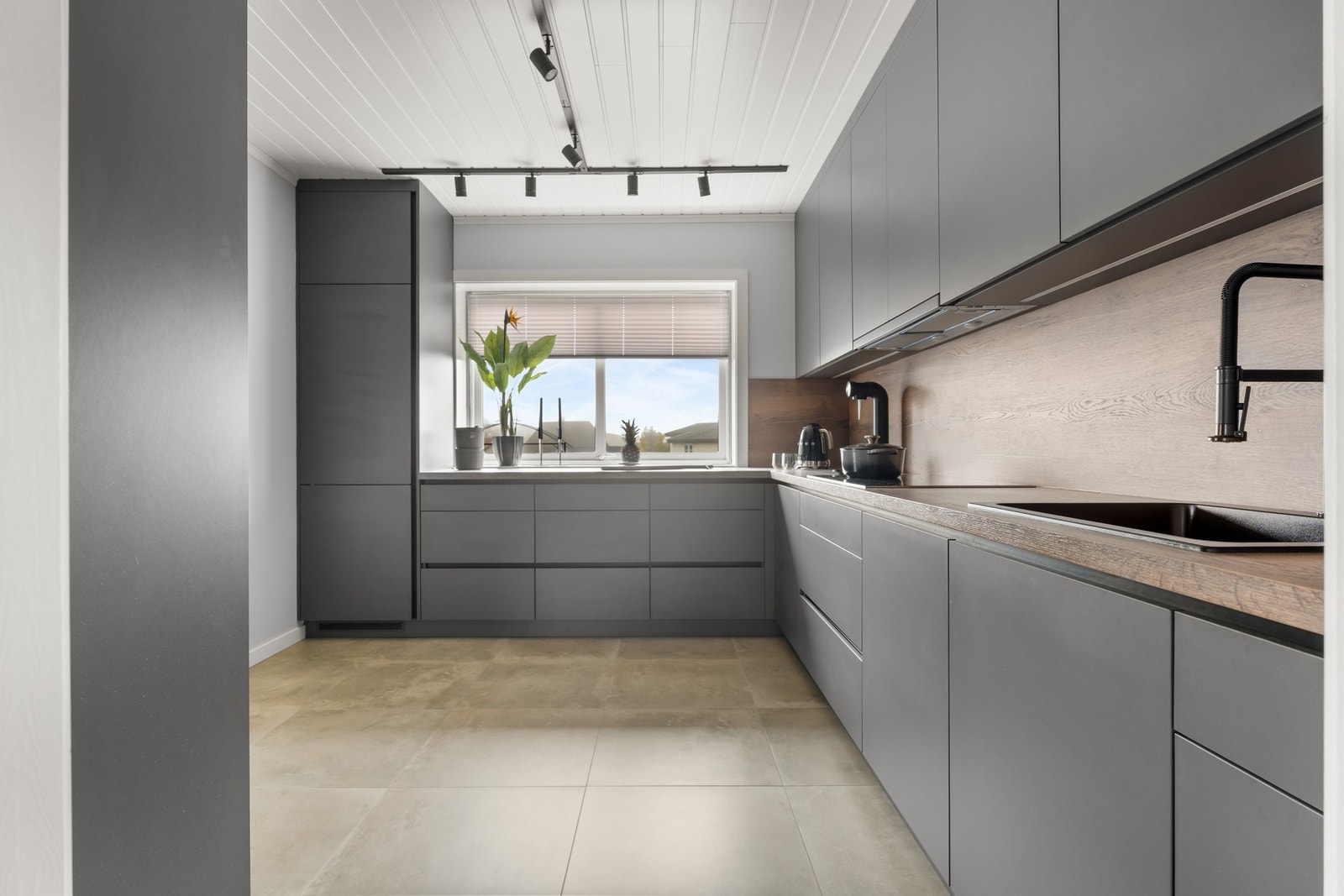 Kjøkkenet er delikat med innredning med slette fronter og høye overskap Galleribilde