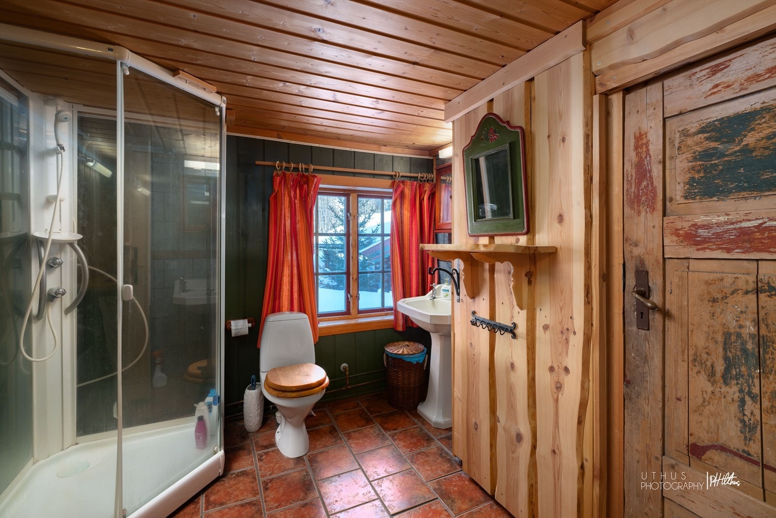 Badet har flis på gulv, vegger med panel og tak med panel.
Installert dusjkabinett, søyleservant og porselen toalett Galleribilde