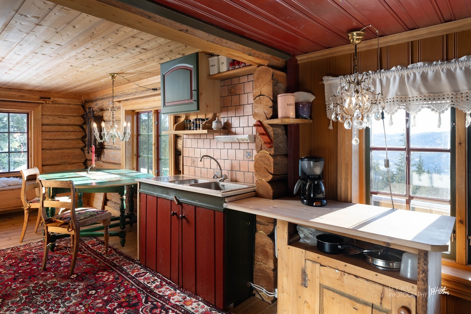 Kjøkkenet har innredning med profilerte fronter. Benkeplaten er av laminat og furu. Nedfelt vask og skyllekum. Det er kjøl/fryseskap og komfyr på gass/strøm. Galleribilde