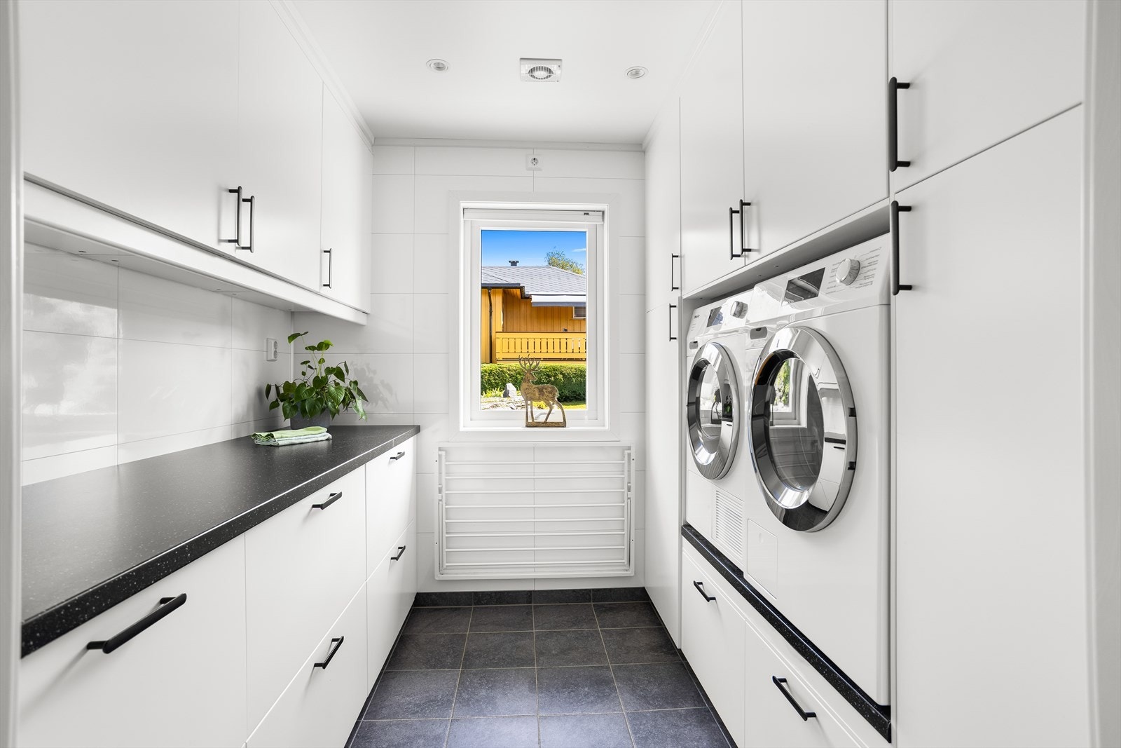 Praktisk vaskerom fra 2021 med innredning med slette fronter og opplegg for vaskemaskin og tørketrommel. Galleribilde