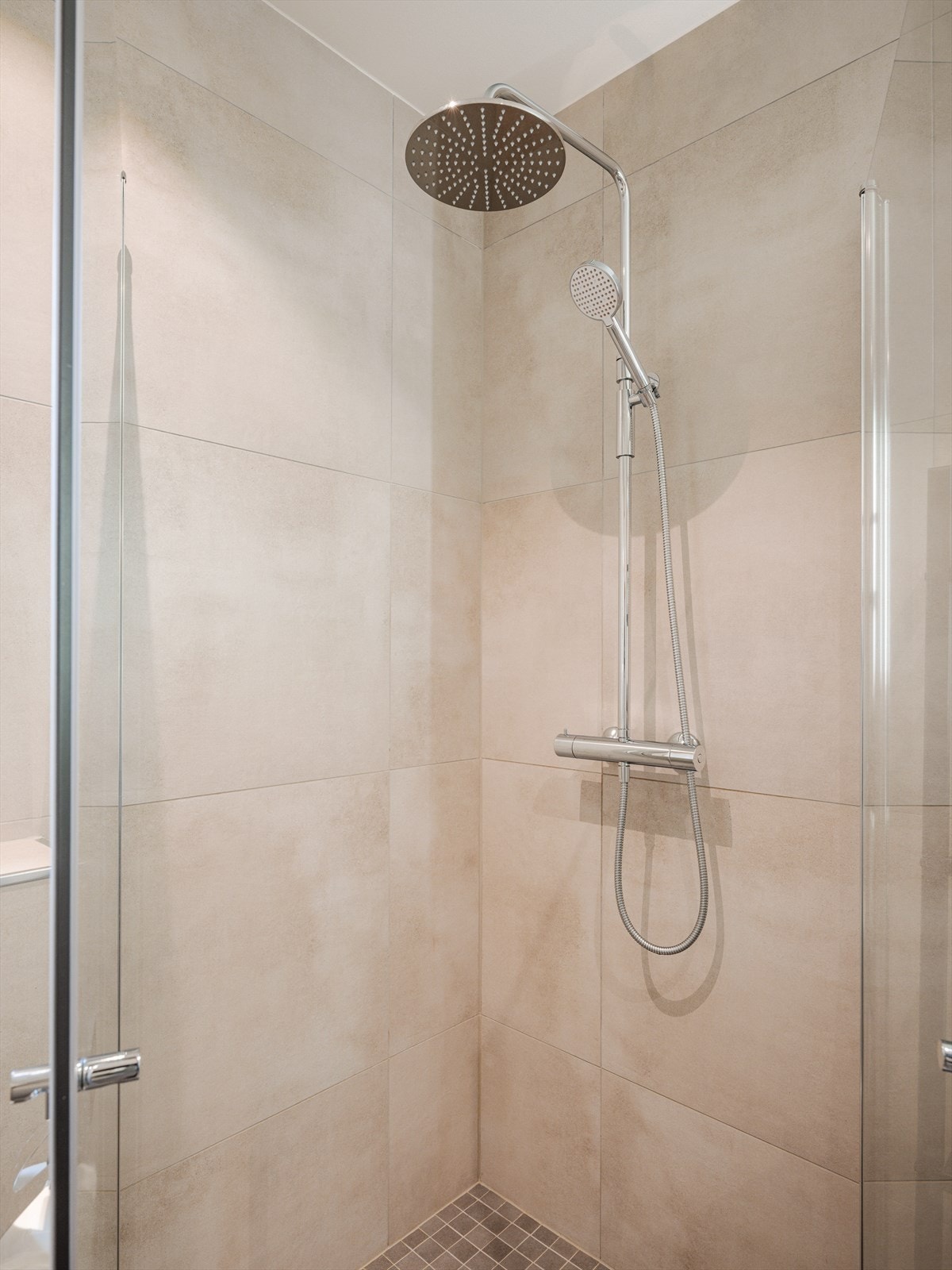 Rommet har gulvvarme og er utstyrt med dusjhjørne med innfellbare glassdører og blandebatteri med dobbelt dusjhode. Galleribilde