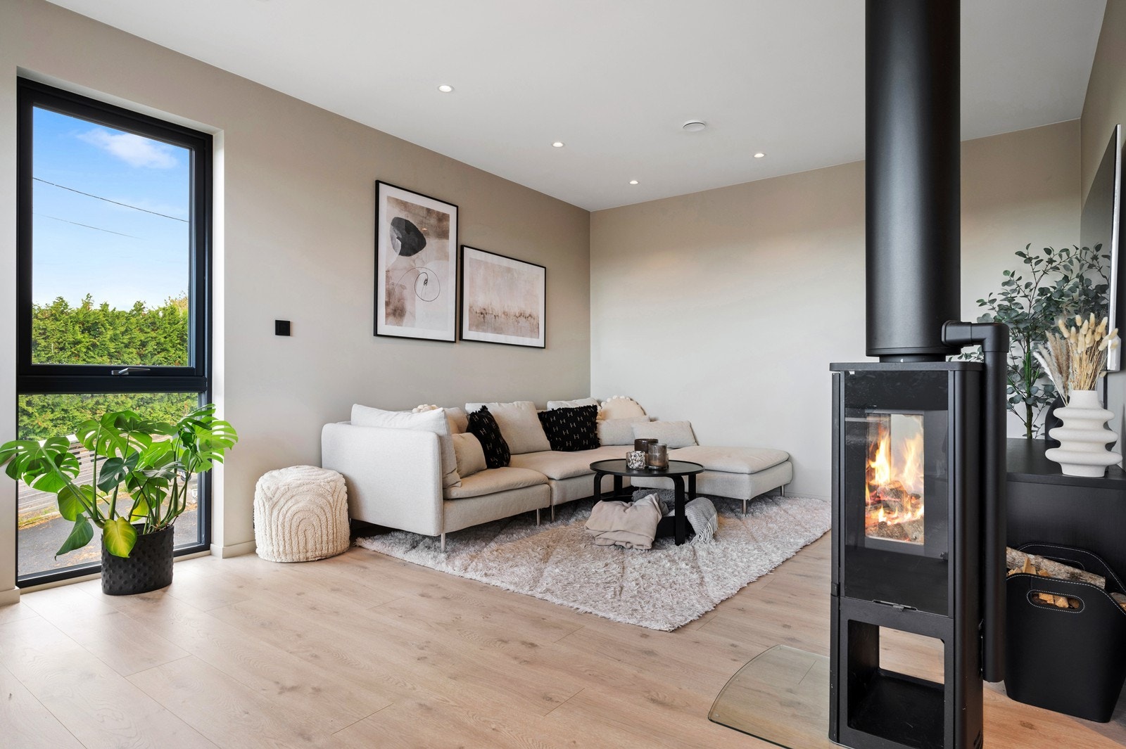 Lys og pen stue med tidsriktig en-stavs laminat på gulvet, slette vegger og tak, med spotter i taket. En dekorativ peisovn varmer godt på kaldere dager Galleribilde