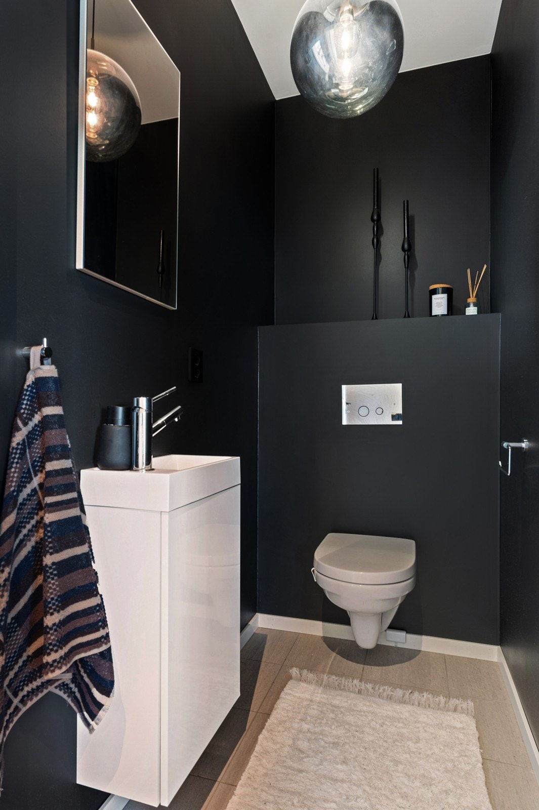 Praktisk, separat toalettrom i 1. etasje, malt i en dyp blåtone. Det er innredet med hvitt servantskap med speil over, og vegghengt wc Galleribilde