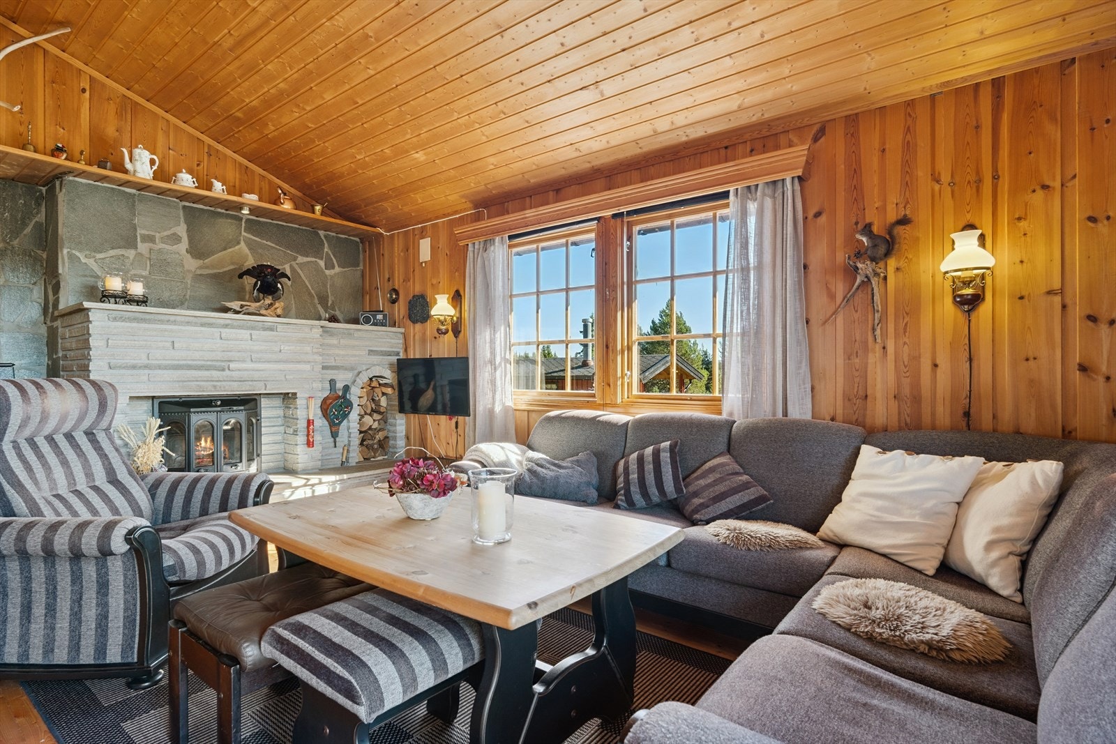 Koselig stue med panelte overflater og tregulv. Den flotte peisen med innsats, troner som et møbel i rommet. Galleribilde