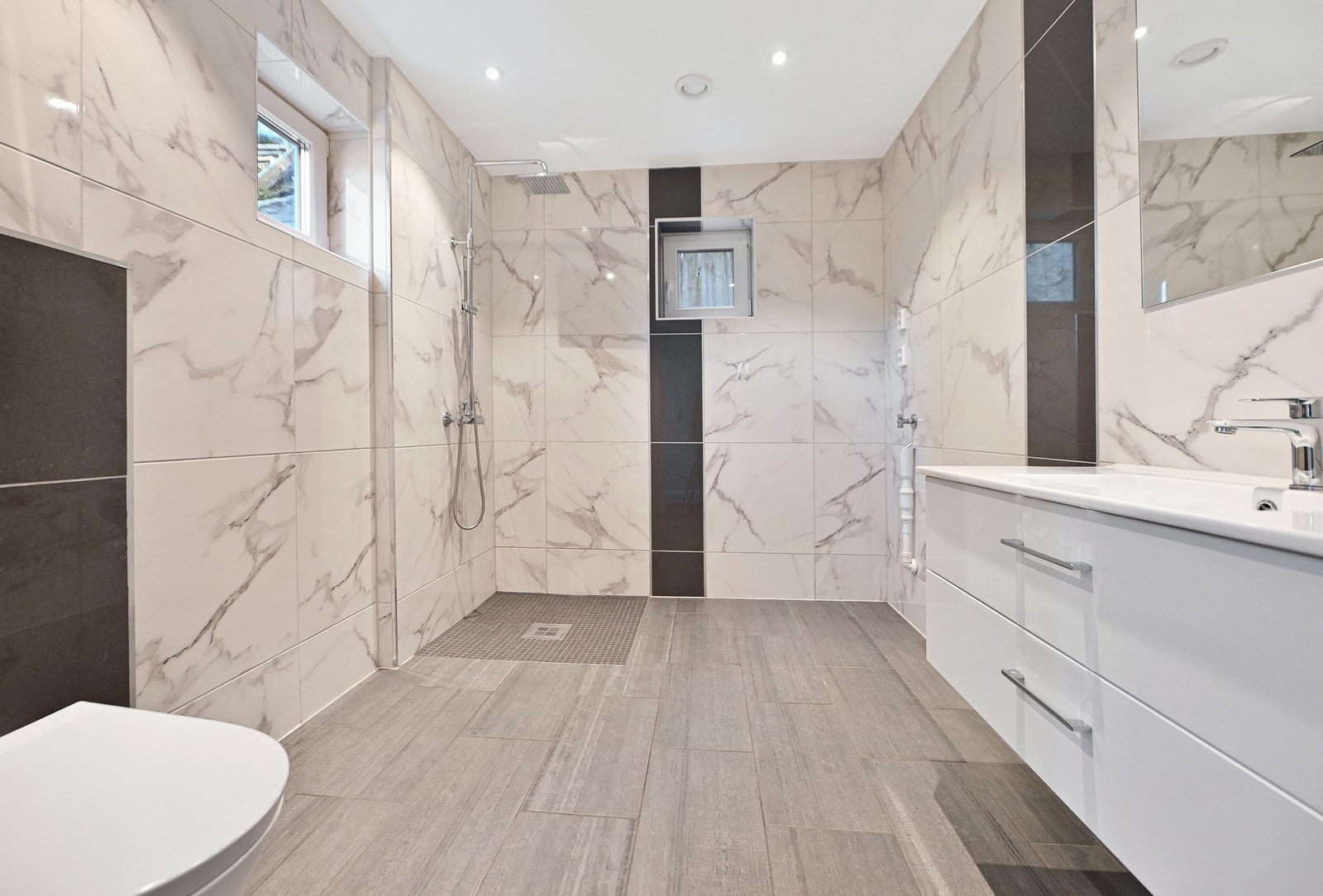 Vegghengt toalett, mosaikkfliser i dusjsonen, opplegg for vaskemaskin. Galleribilde