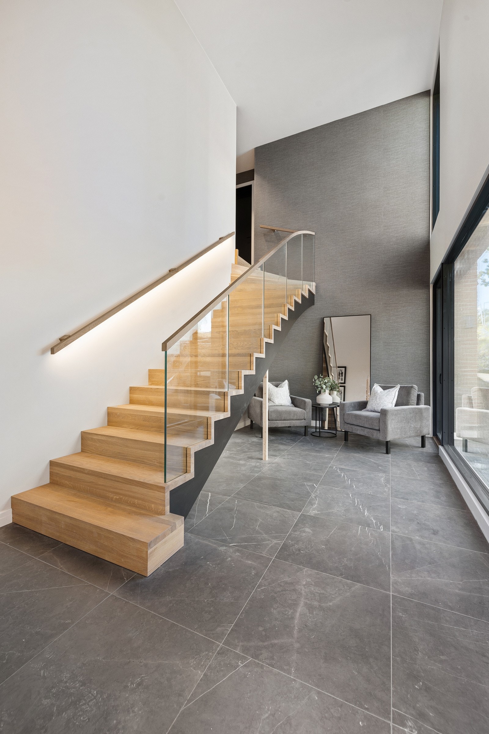 Om du ikke velger å ta heisen opp til leilighetens hovedetasje, har leiligheten også privat adkomst fra terreng til stor og innbydende hall. Trappeløp opp til leilighetens hovedetasje. Utgang fra hall til stor terrasseplatting.