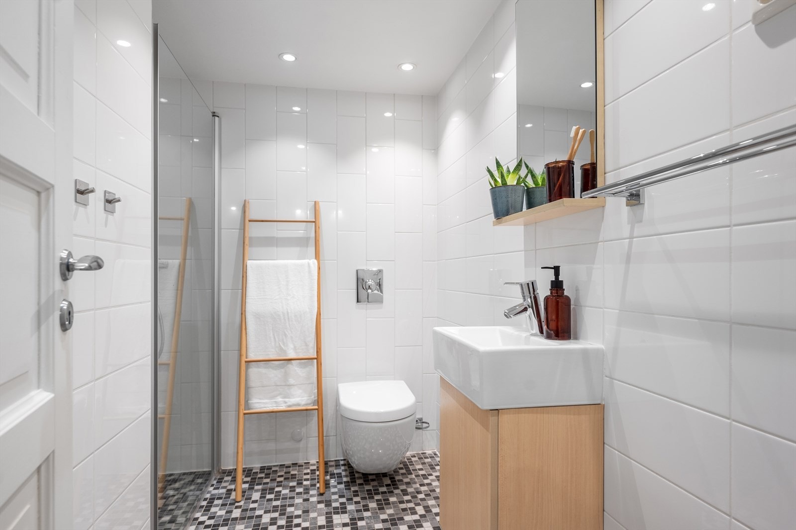 Badet i underetasjen har lyse fliser på veggene og grå mosaikkfliser på gulvet med varmekabler. Her er vegghengt toalett, dusj med svingbar dusjdør, servant i skapinnredning og speil. Se tekst under ferdigattest ang kjeller som ikke er godkjent Galleribilde