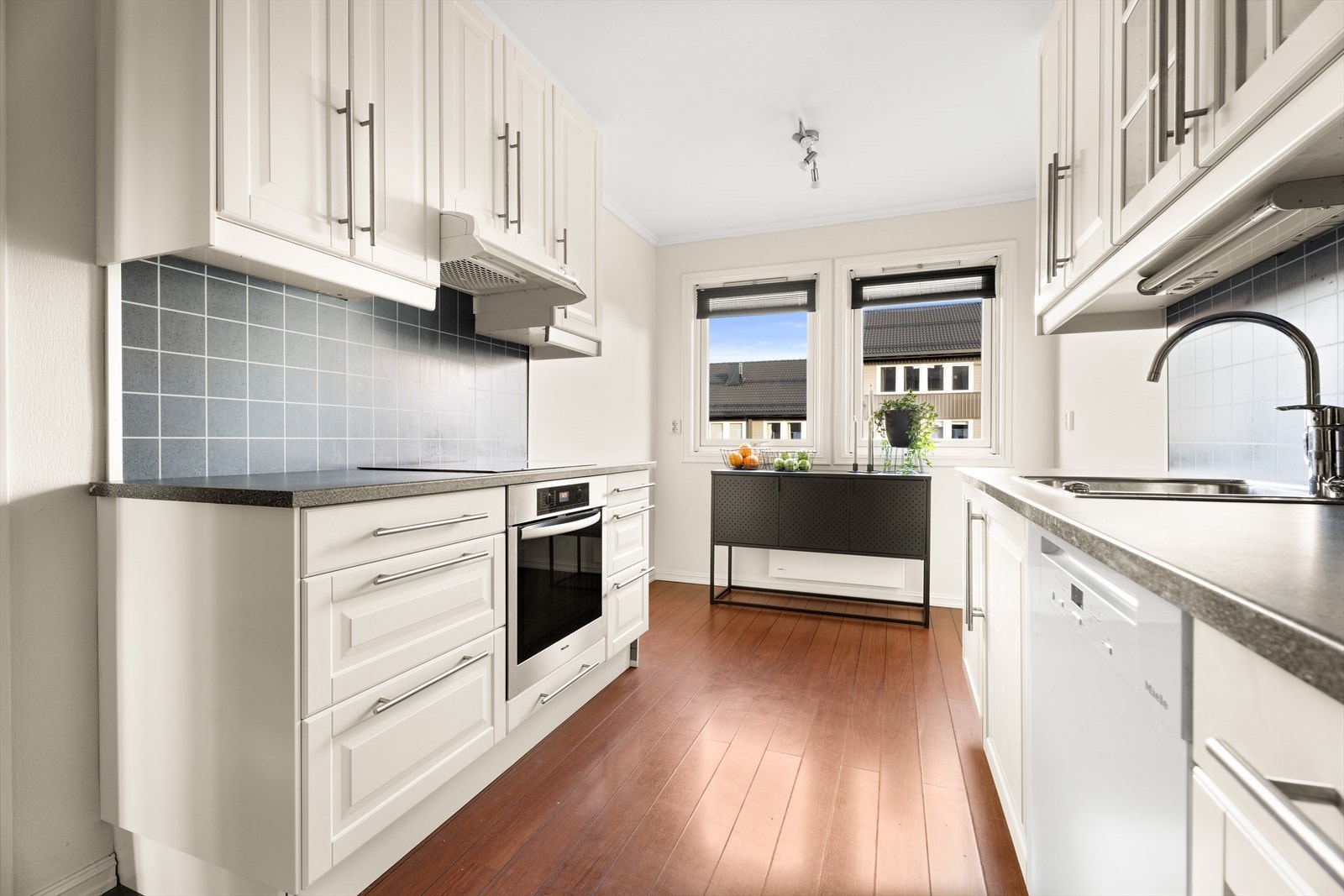 Innredningen kombinerer skuffer og skap for fleksibel og god oppbevaringsplass, og enkelte overskap har elegante glassfronter som tilfører kjøkkenet et lett og eksklusivt uttrykk. Galleribilde