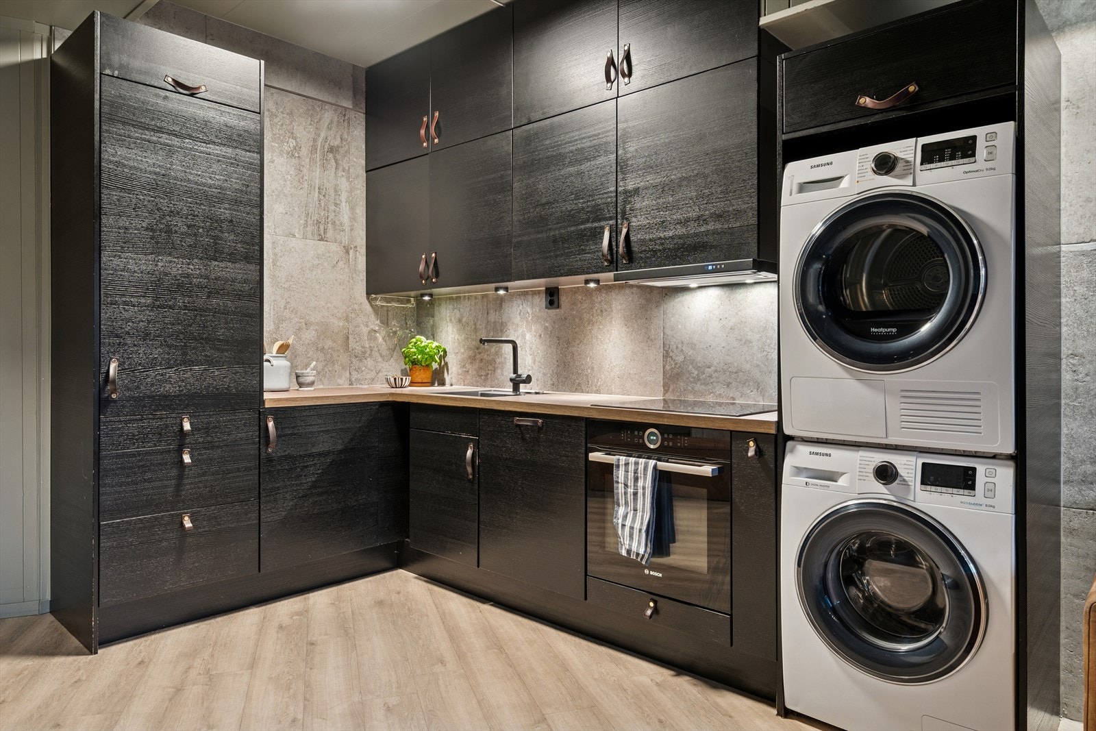 Kjøkkenet har innredning fra 2020 med sorte fronter og lys benkeplate med nedfelt sort servant - Deler av innredningen er takhøy og det er god belysning med downlights under overskapene Galleribilde