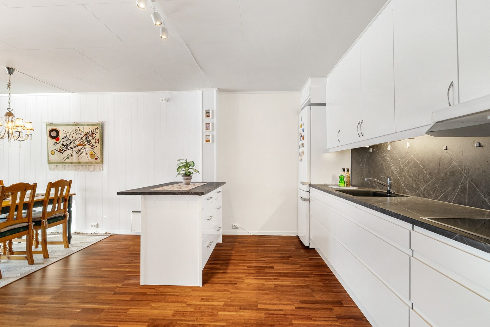 Kjøkkenet avgrenses fra oppholdsrommet med en praktisk kjøkkenøy, som gir ekstra arbeidsflate og fungerer som en naturlig overgang mellom sonene Galleribilde