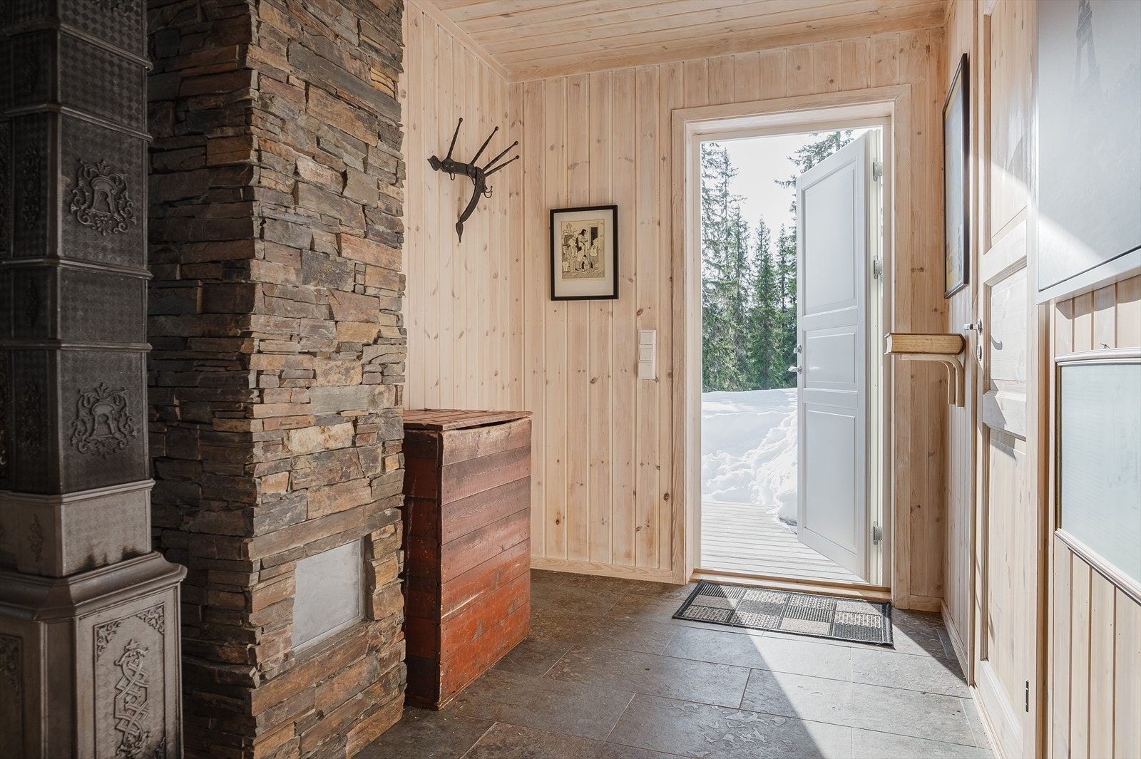 Du ønskes velkommen inn til en praktisk entré med steinfliser på gulv med varmekabler i, og opphengsmuligheter for tøy. Entréen har åpen adkomst inn til stue- og kjøkken, samt dør inn til bad. Galleribilde