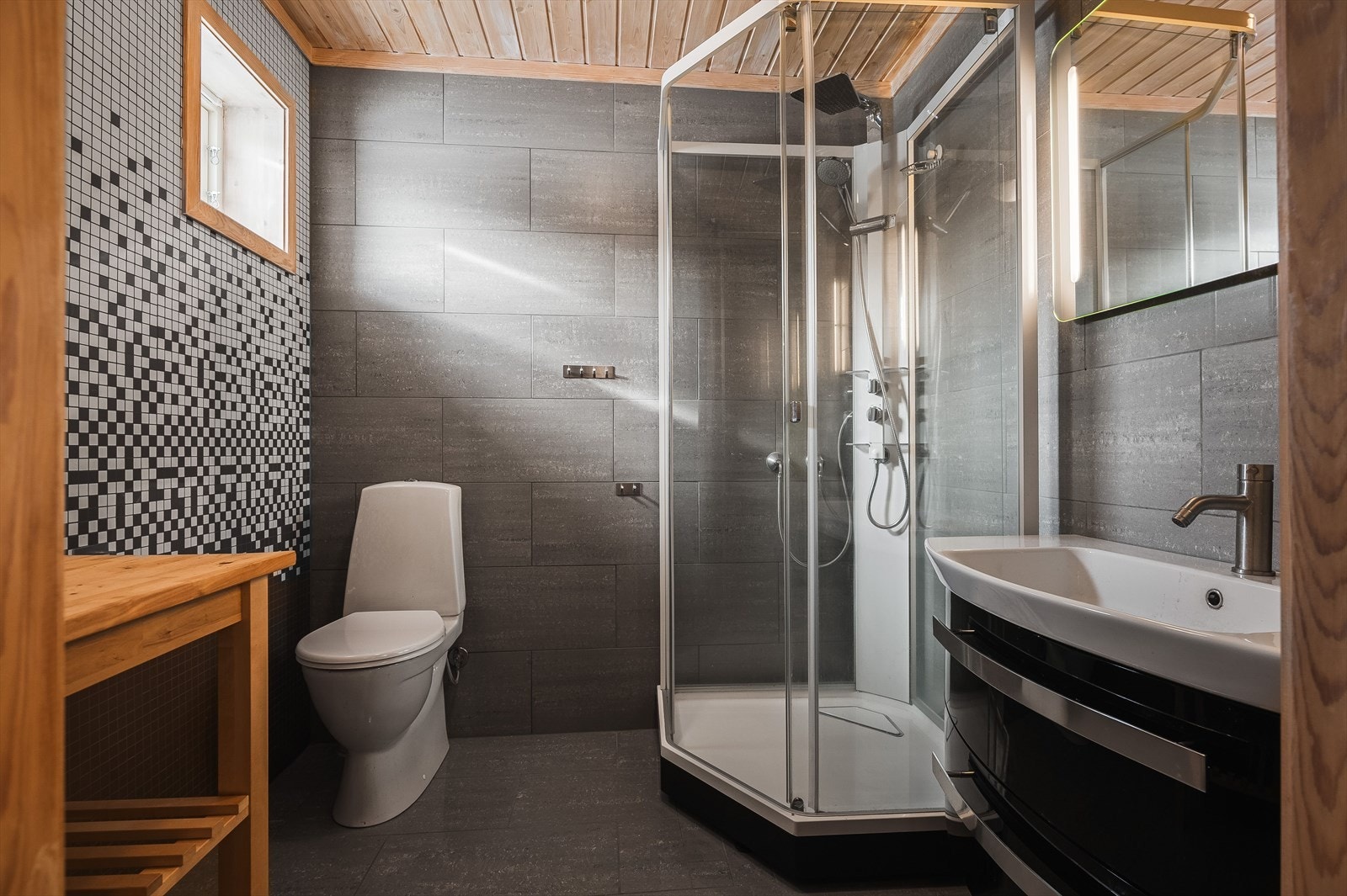 Pent bad med flislagte gulv- og vegger, med varmekabler i gulvet. Badet er innredet med servant som er nedfelt i innredning, et belyst speil, dusjkabinett og frittstående toalett. Opplegg for vaskemaskin, og ventilasjon via elektrisk vifte på vegg. Galleribilde