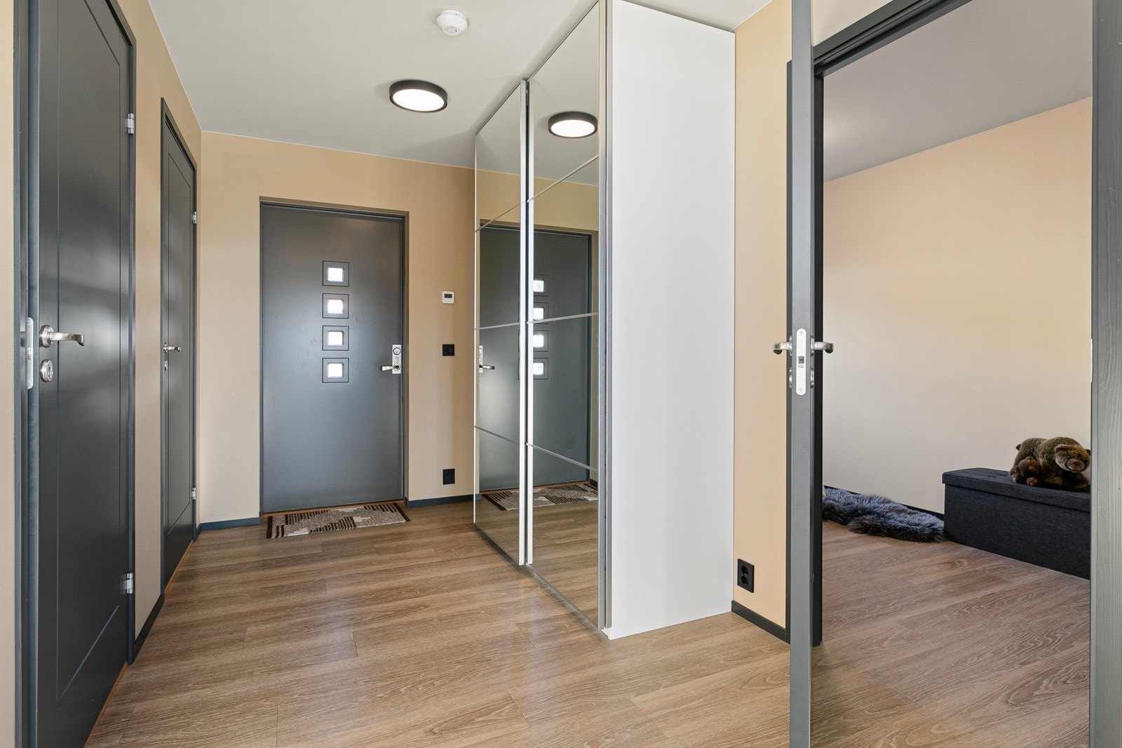 Tiltalende entre med enstavs laminat på gulv med gulvvarme og lysmalte, slette veggflater som gir et godt førsteinntrykk av boligen. Galleribilde