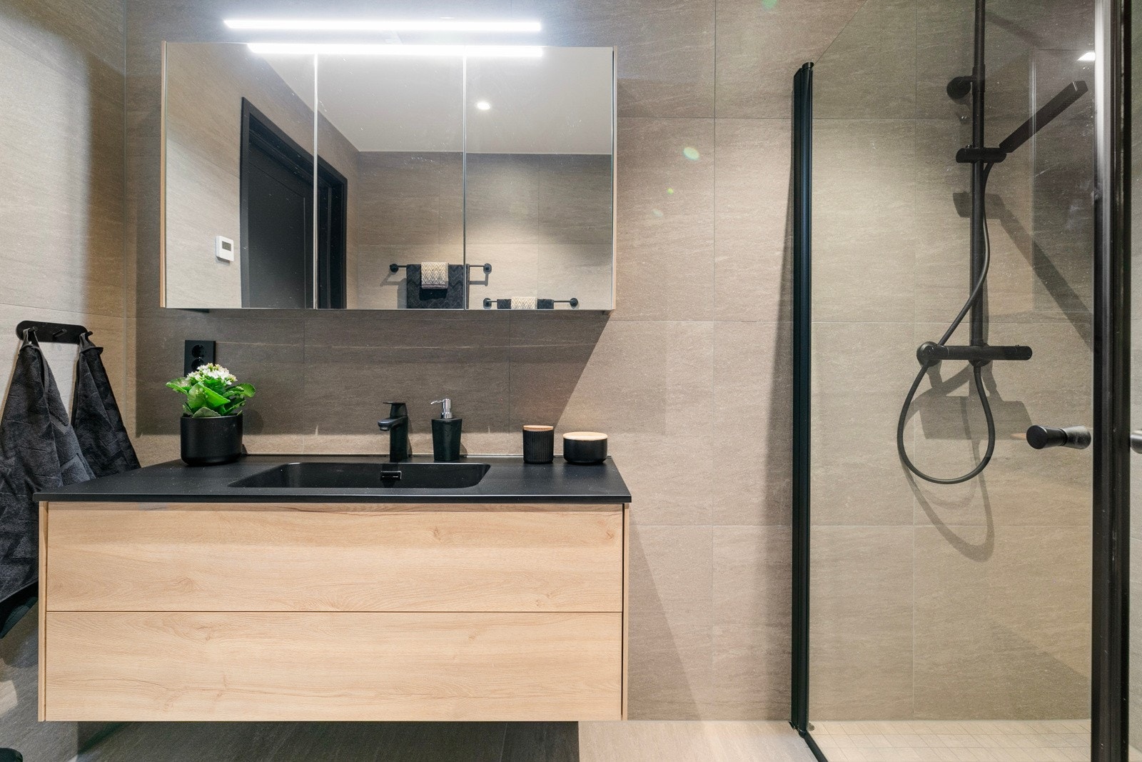 Innredningen består av benk med heldekkende vask og overskap med speildører og overlys. Videre har badet et separat dusjhjørne med glassdører og innebygget toalett. Galleribilde