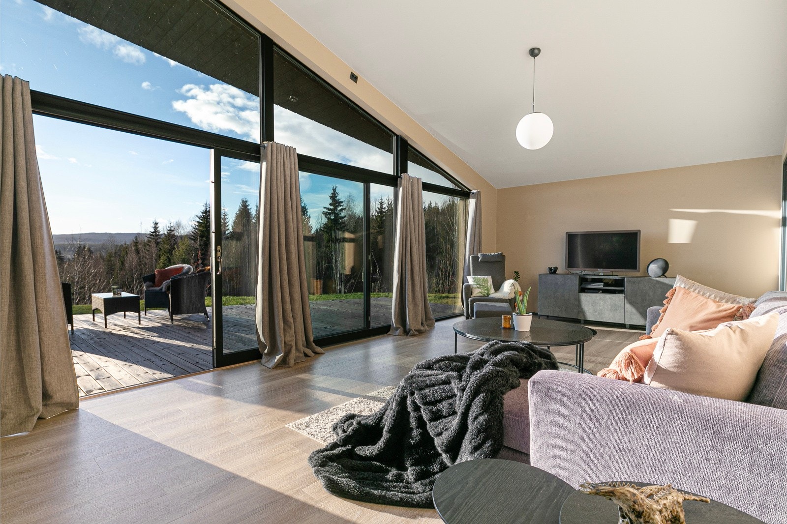 Stuen fremstår som meget innbydende i en dus og delikat fargepalett - med en mørkere profil på vinduer og terrassedør. Galleribilde