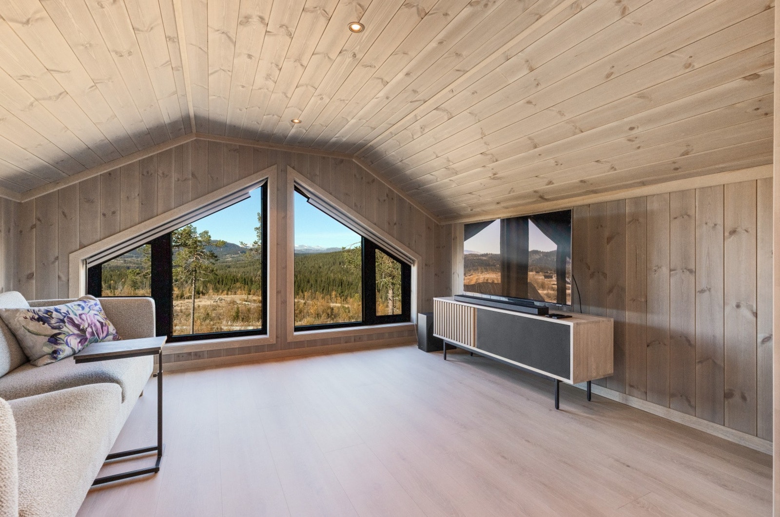 Loftstuen har vinduer fra gulv til himling, noe som får utsikten og dagslyset til å flomme inn Galleribilde