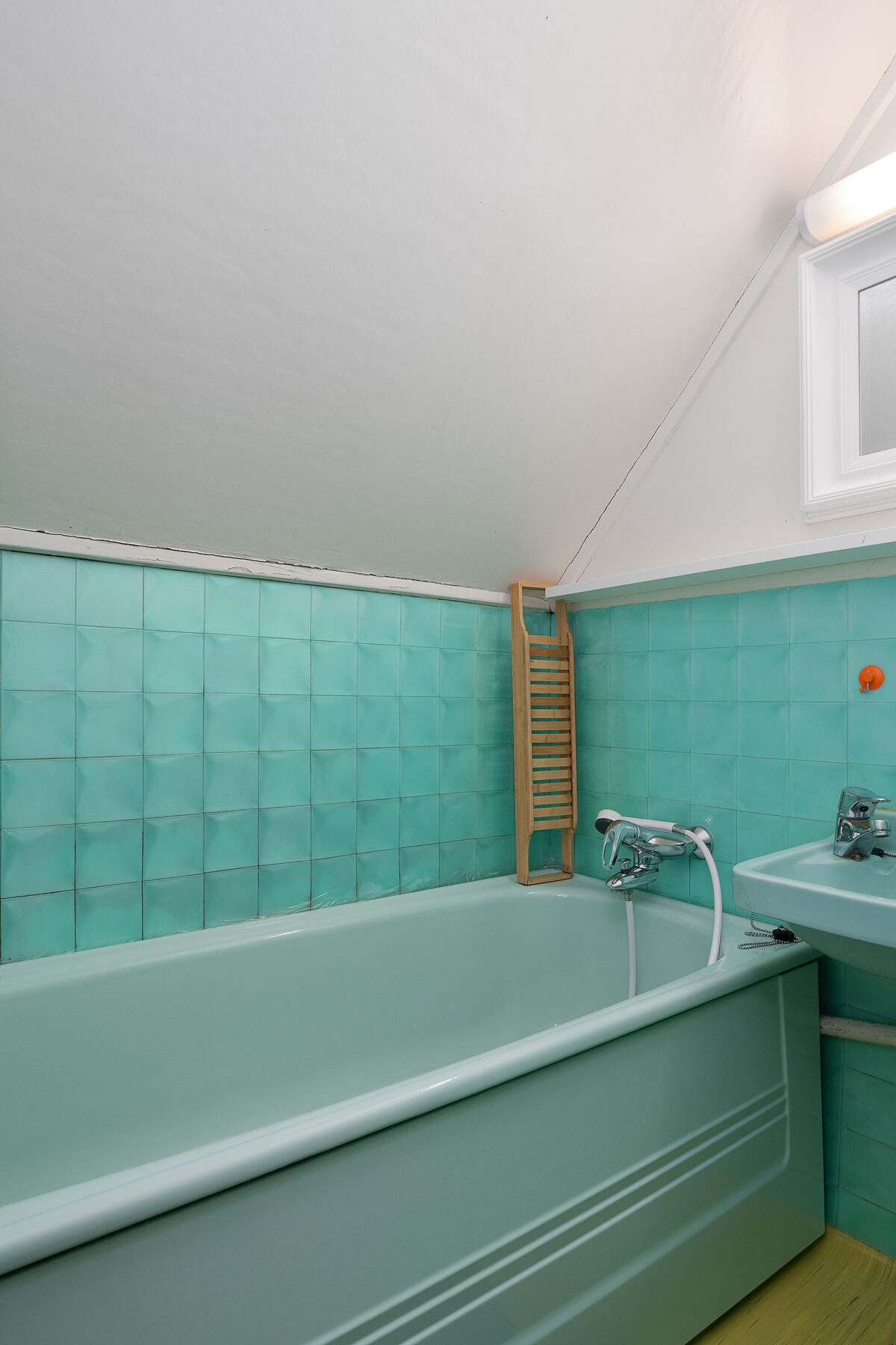 Eldre bad, mest sannsynlig fra opprinnelig byggeår (tilbygd del). Badet er utført med malte plater på vegger, stedvis med pålimte plastfliser og våtromsbelegg på gulv. Rommet er utstyrt med badekar og servant. Galleribilde