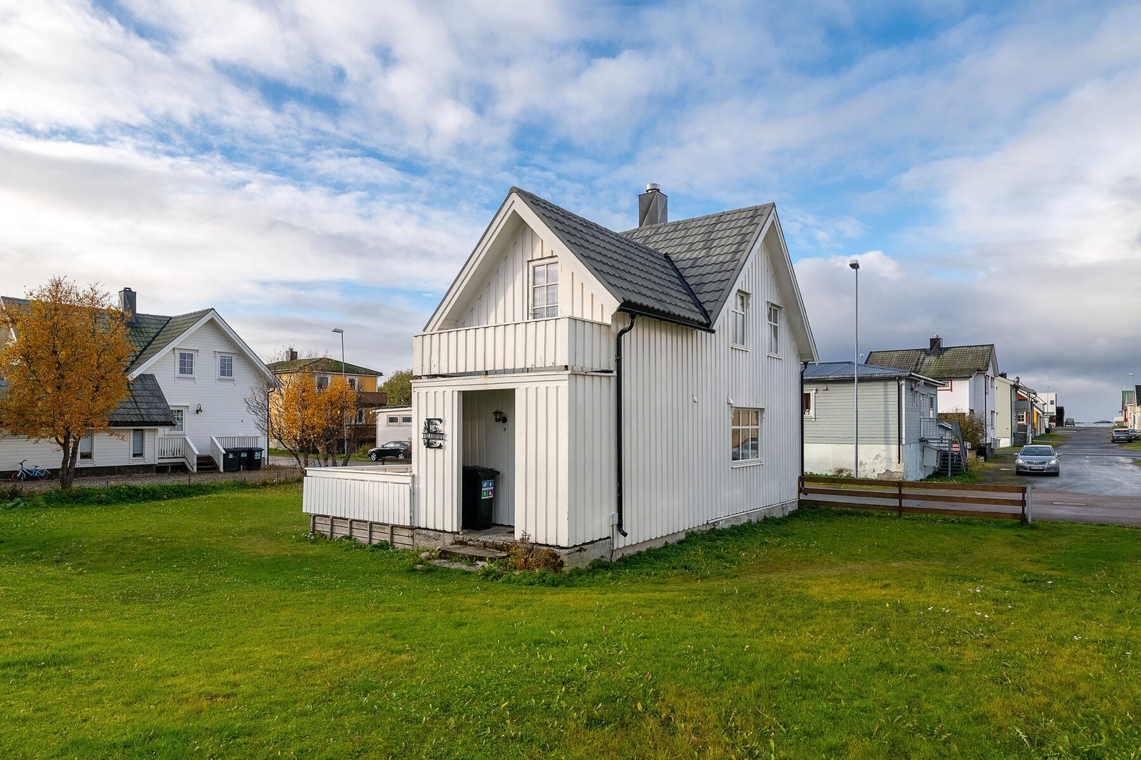 Fasade og uteområde. Den flate tomten er opparbeidet med plen, og er delvis inngjerdet. Galleribilde