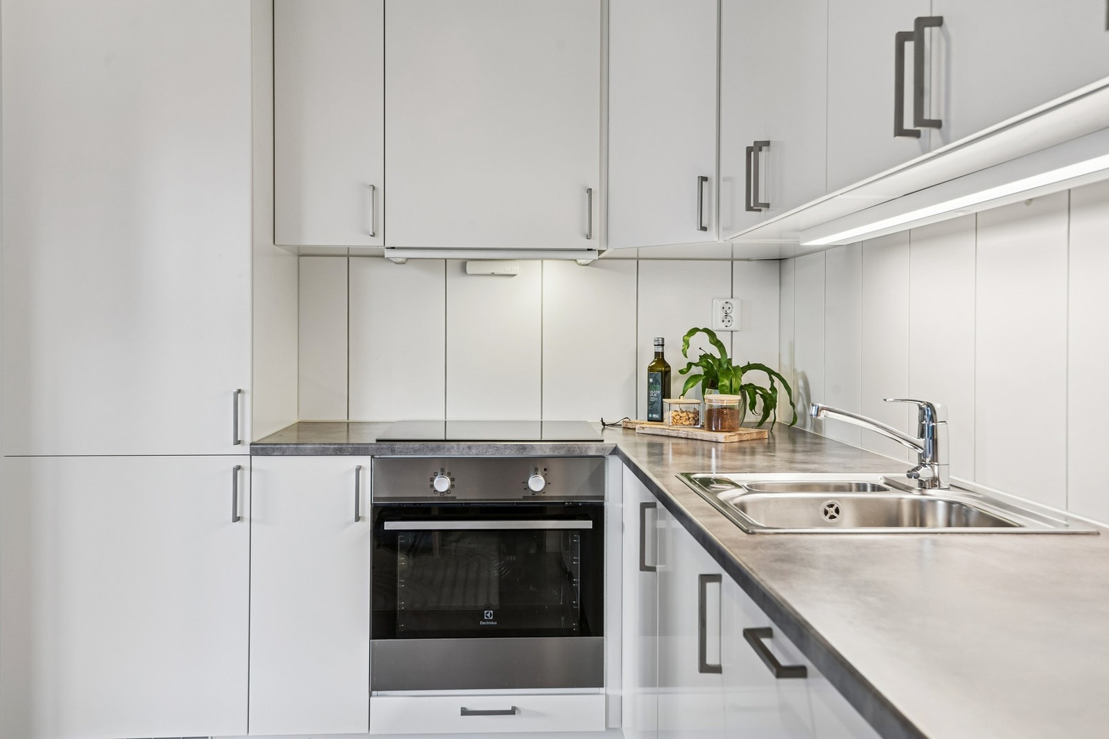 Kjøkkenet er innredet med hvite, glatte fronter og laminert benkeplate som gir et rent og moderne uttrykk. Galleribilde