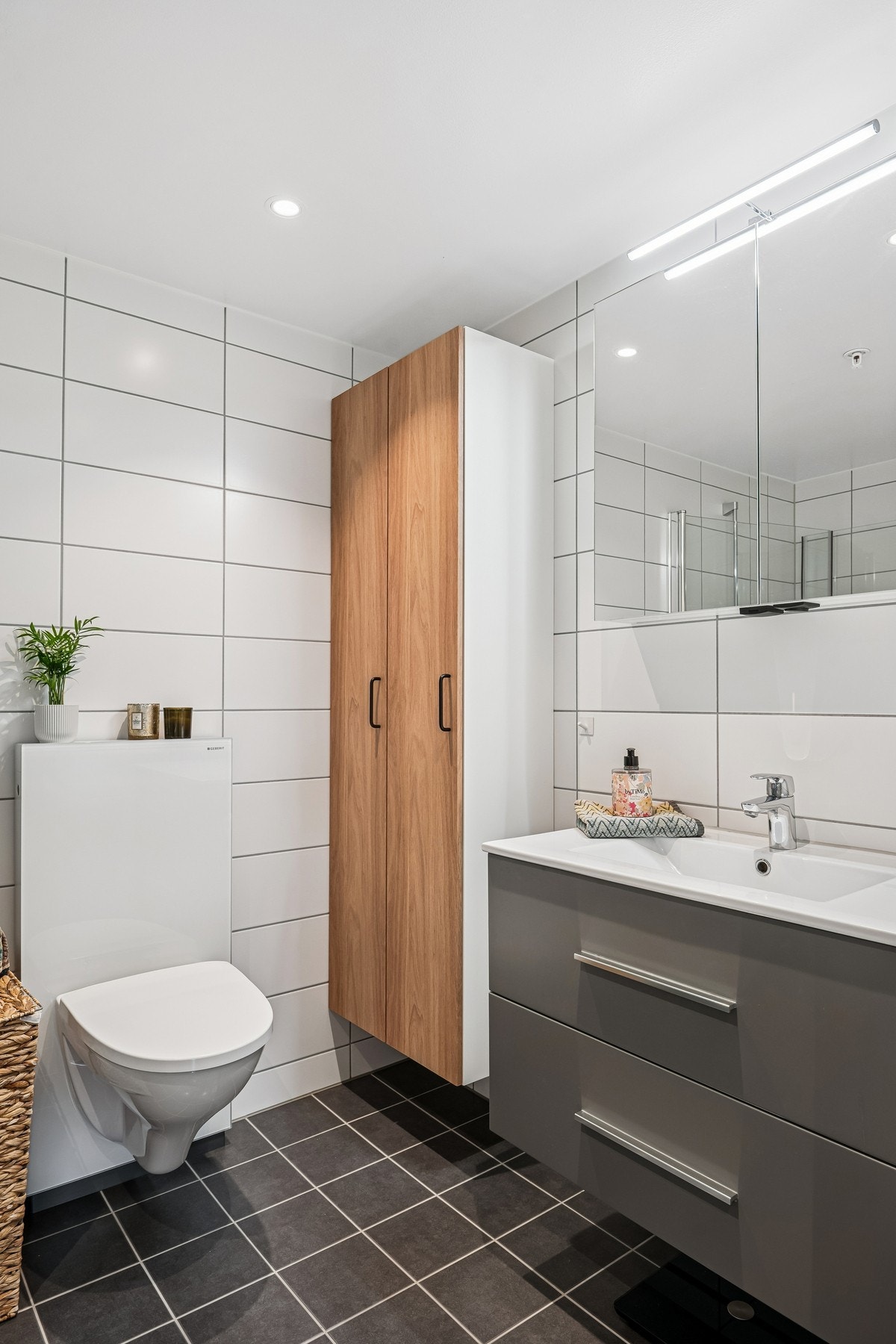 Badet er moderne og funksjonelt med flislagte overflater, vegghengt toalett, servant med underskap og dusjhjørne. Galleribilde