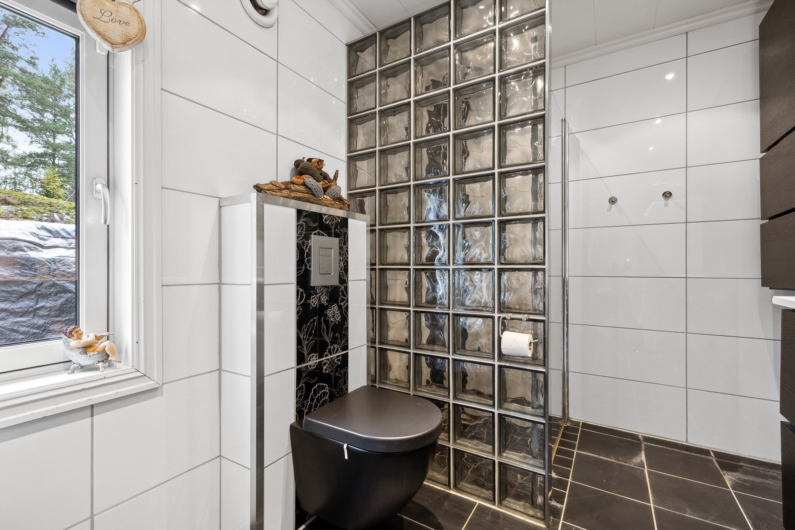 Badet er utstyrt med toalett, dusjnisje med glassdør, innredning med servant, veggskap og opplegg for vaskemaskin. Galleribilde