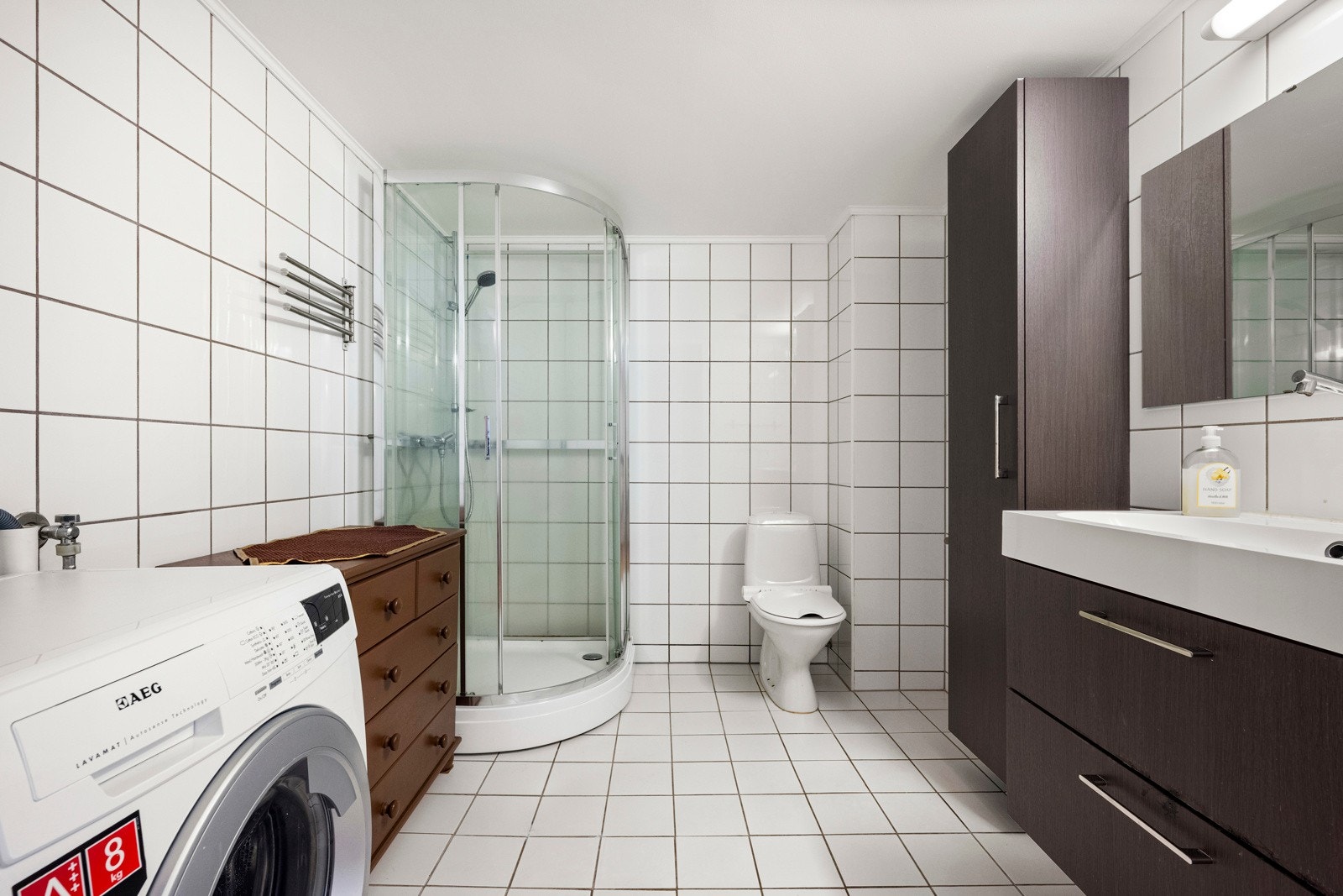 Baderommet har vegghengt servantinnredning med skuffer, dusjkabinett fra 2019 og opplegg for vaskemaskin. Galleribilde