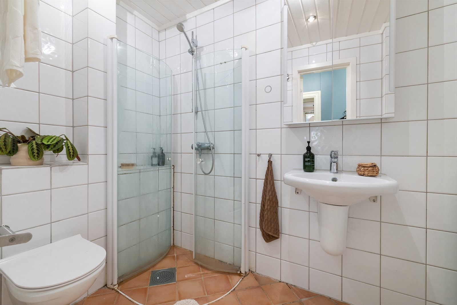 Badet er utstyrt med dusjhjørne med innfellbare dusjdører og blandebatteri fra Oras, veggmontert toalett og hvit servant med blandebatteri fra Oras. Galleribilde