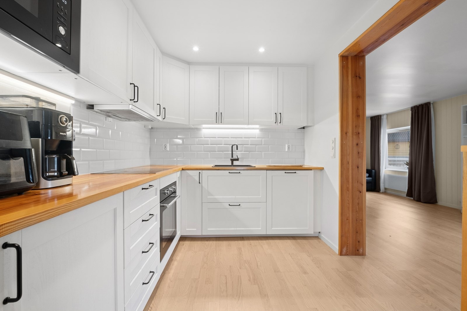 Kjøkkenet har en moderne innredning fra 2021 med profilerte, hvite fronter og massive benkeplater av furu som gir et lunt og stilrent uttrykk. Galleribilde