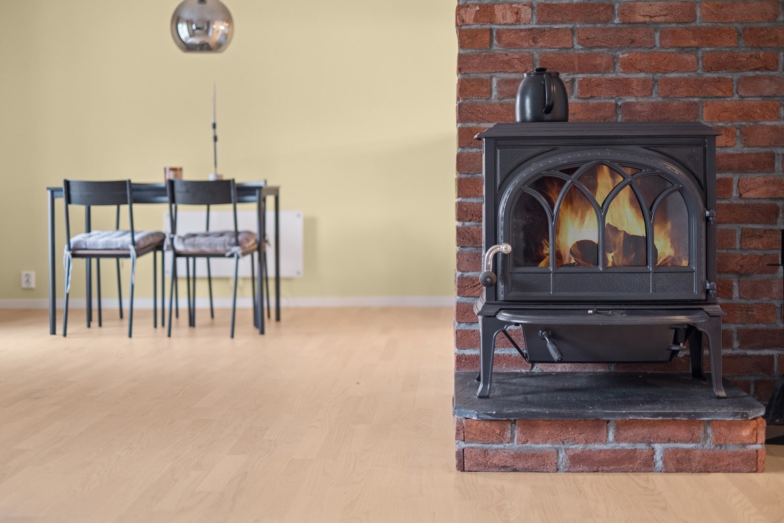 Midt i rommet står en teglsteinsmur med vedovn, som gir både varme og karakter til rommet. Galleribilde