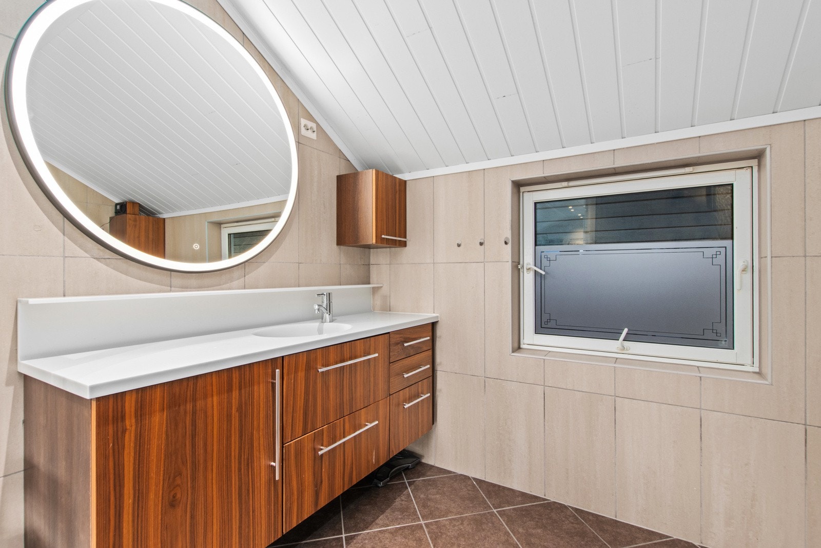 Flislagt bad med varmekabler, servant med lagerplass, speil med belysning, klosett og badekar med dusj. Galleribilde