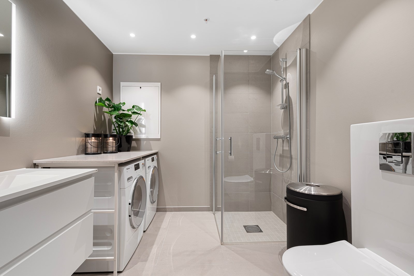 Lekkert bad med malte plater på vegger, downlights i himling og flislagt gulv med varmekabler. Innredningen er bestående av vegghengt klosett, flislagt dusjnisje og baderomsinnredning med speil Galleribilde